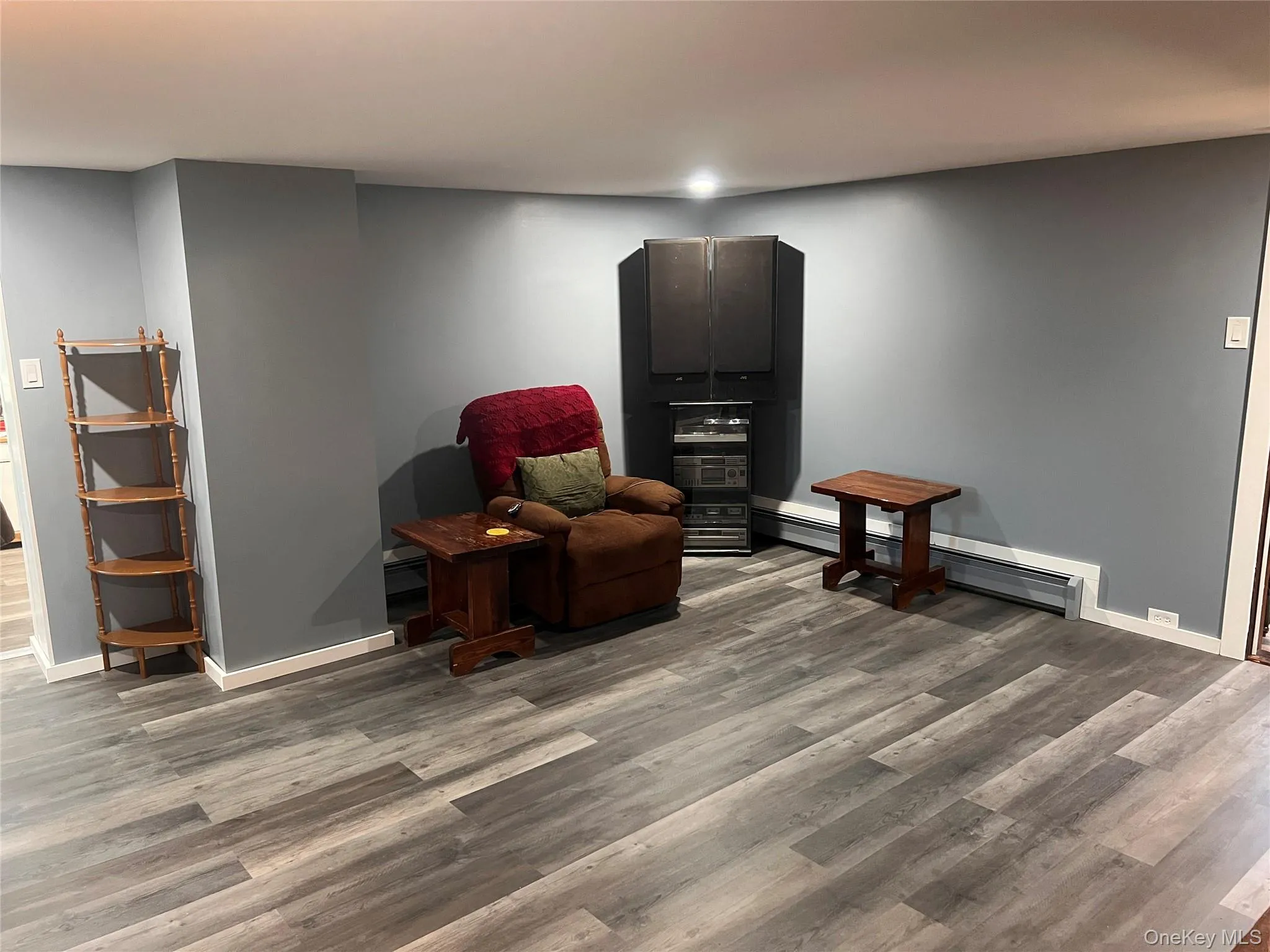Living area with wood finished floors and a baseboard radiator Living area with wood finished floors and a baseboard radiator