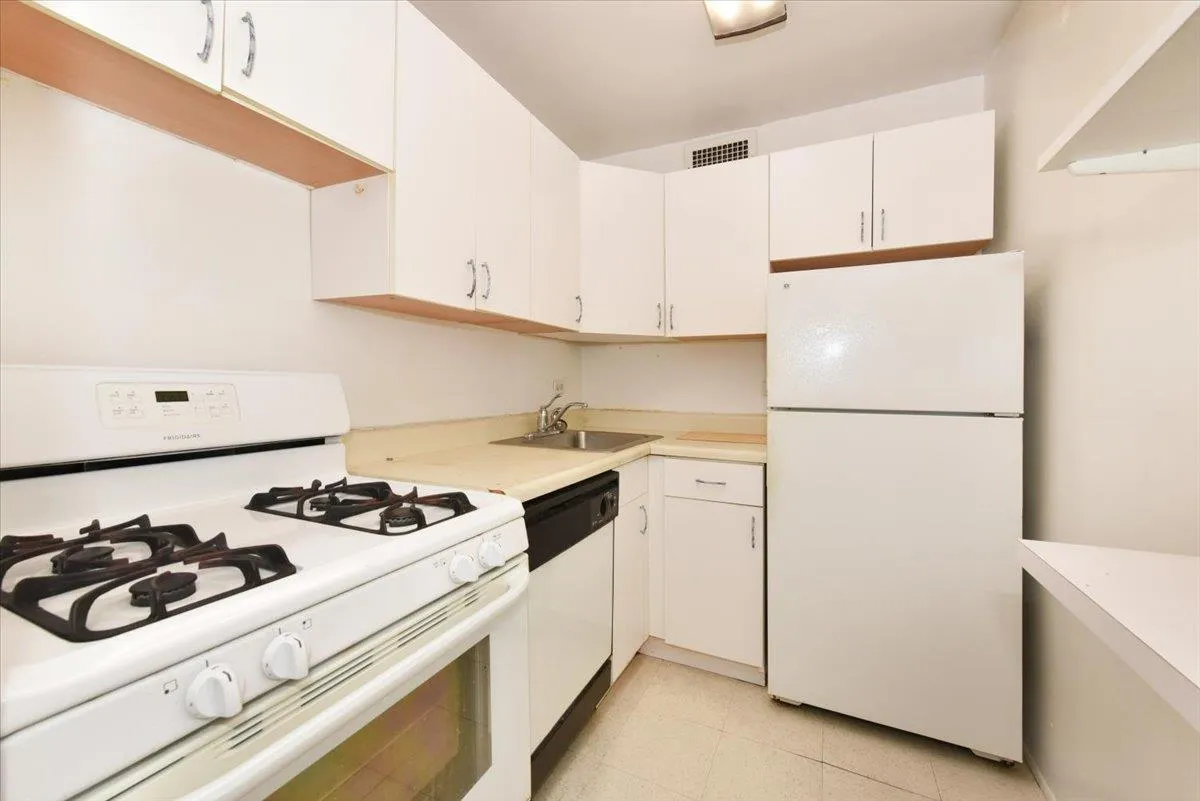 Kitchen featuring white cabinetry, white appliances, light countertops, and a sink Kitchen featuring white cabinetry, white appliances, light countertops, and a sink