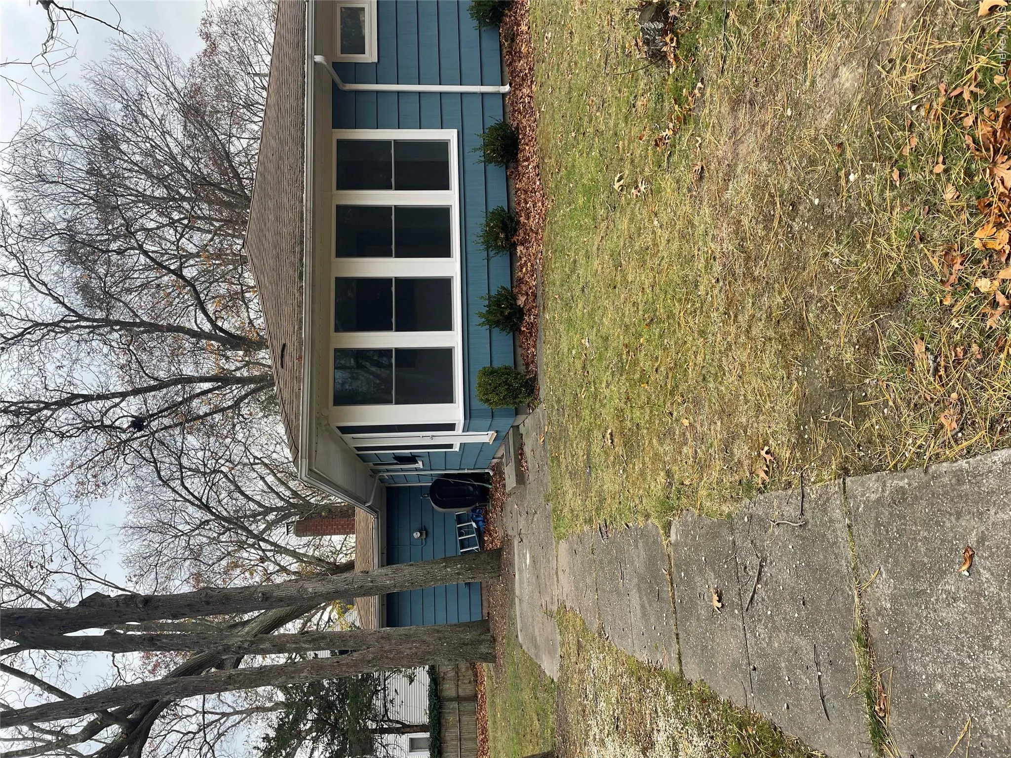 View of front facade featuring a front yard, oil tank, roof with shingles, and a chimney View of front facade featuring a front yard, oil tank, roof with shingles, and a chimney