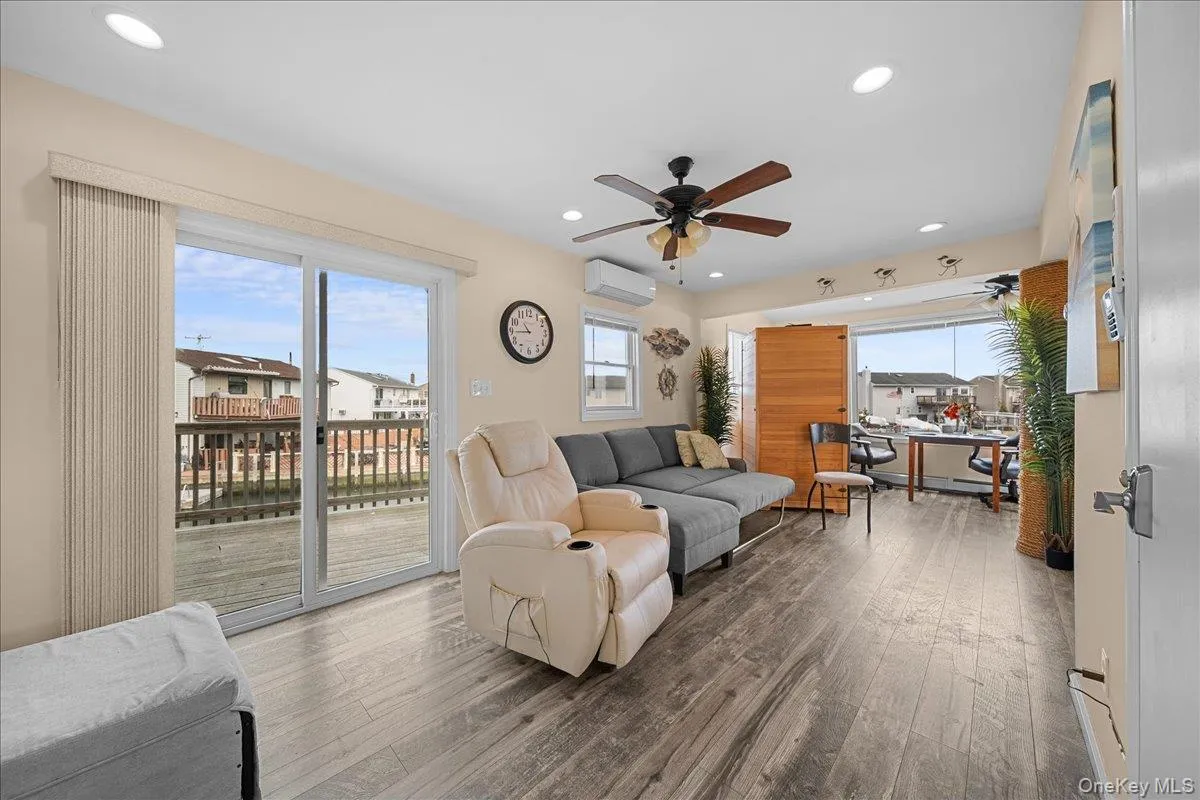 Living area featuring a wall mounted air conditioner, wood-type flooring, ceiling fan, and recessed lighting Living area featuring a wall mounted air conditioner, wood-type flooring, ceiling fan, and recessed lighting