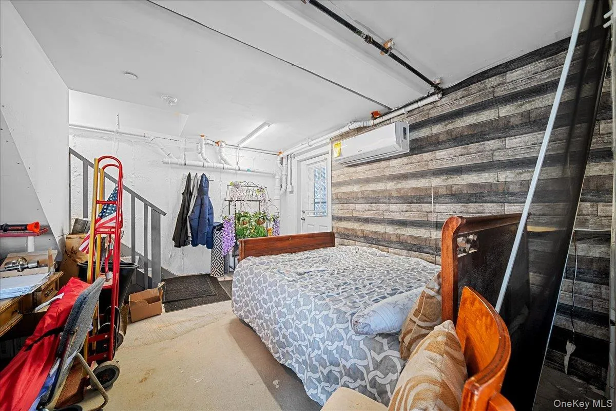 Bedroom with a wall mounted air conditioner, wood walls, and a garage Bedroom with a wall mounted air conditioner, wood walls, and a garage