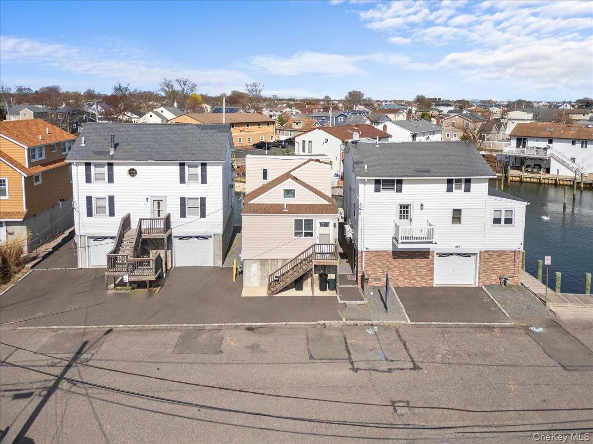 Back of property with an attached garage, aphalt driveway, stairs, and a residential view Back of property with an attached garage, aphalt driveway, stairs, and a residential view