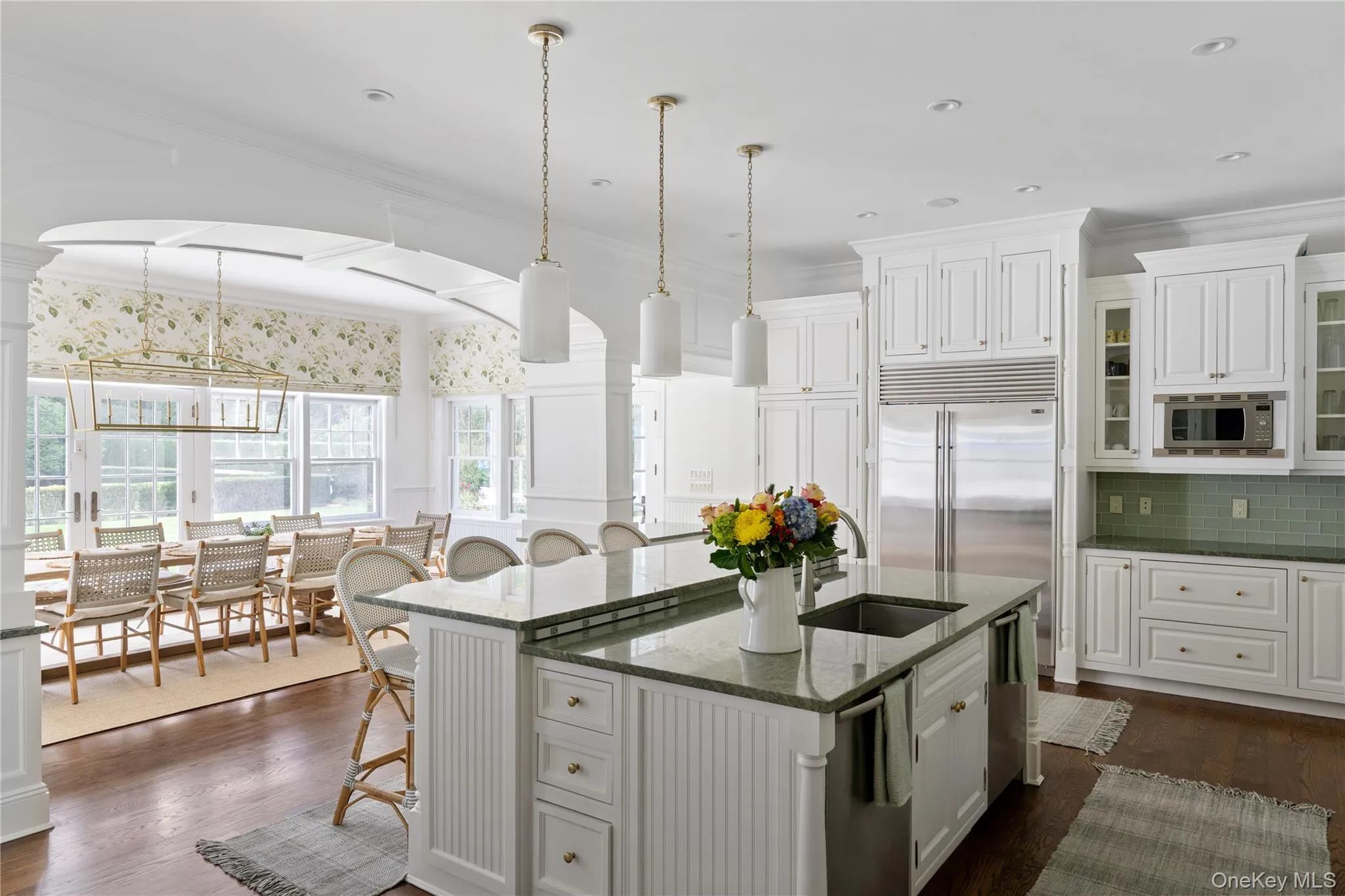 Kitchen with white cabinets, a kitchen island with sink, a sink, a kitchen bar, and built in appliances Kitchen with white cabinets, a kitchen island with sink, a sink, a kitchen bar, and built in appliances