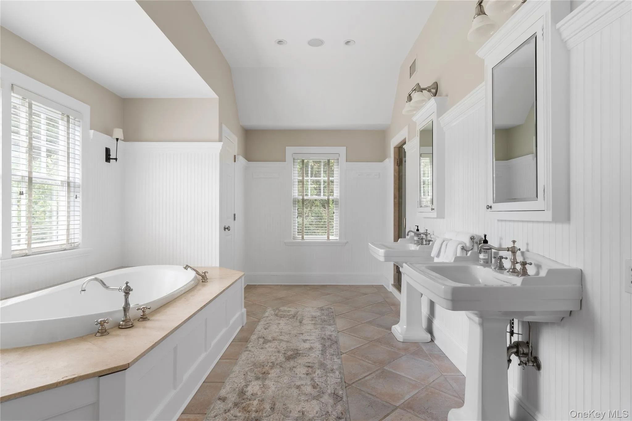 Full bathroom featuring a wainscoted wall, plenty of natural light, tile patterned flooring, a decorative wall, and a garden tub Full bathroom featuring a wainscoted wall, plenty of natural light, tile patterned flooring, a decorative wall, and a garden tub
