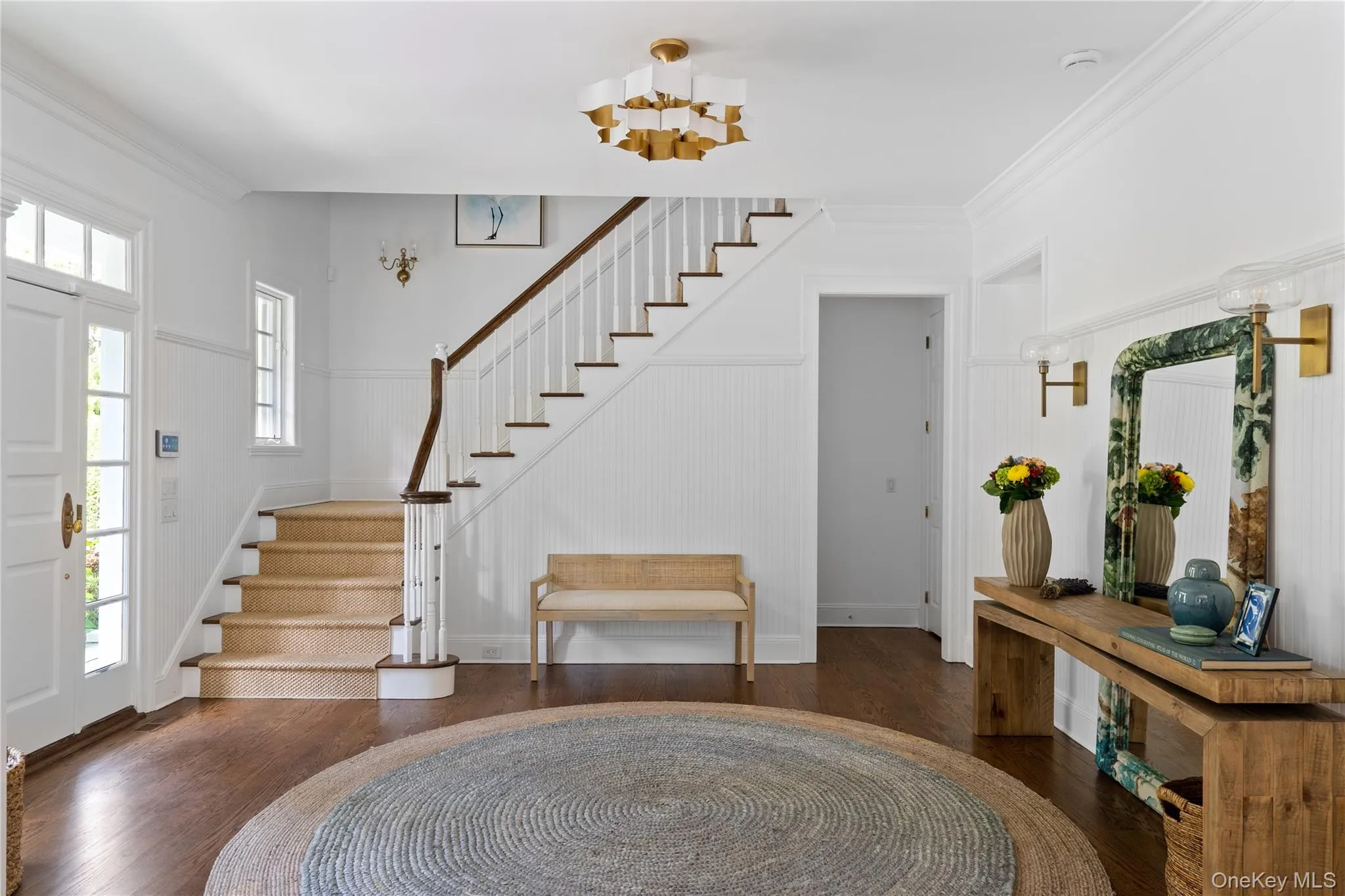 Foyer featuring wood finished floors, crown molding, and stairs Foyer featuring wood finished floors, crown molding, and stairs