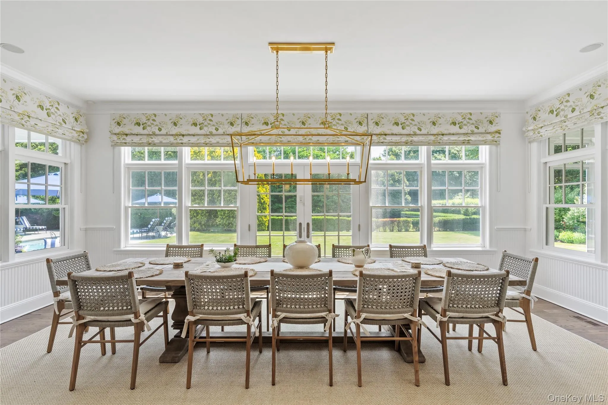 Sunroom featuring ornamental molding, a wainscoted wall, wood finished floors, and a healthy amount of sunlight Sunroom featuring ornamental molding, a wainscoted wall, wood finished floors, and a healthy amount of sunlight
