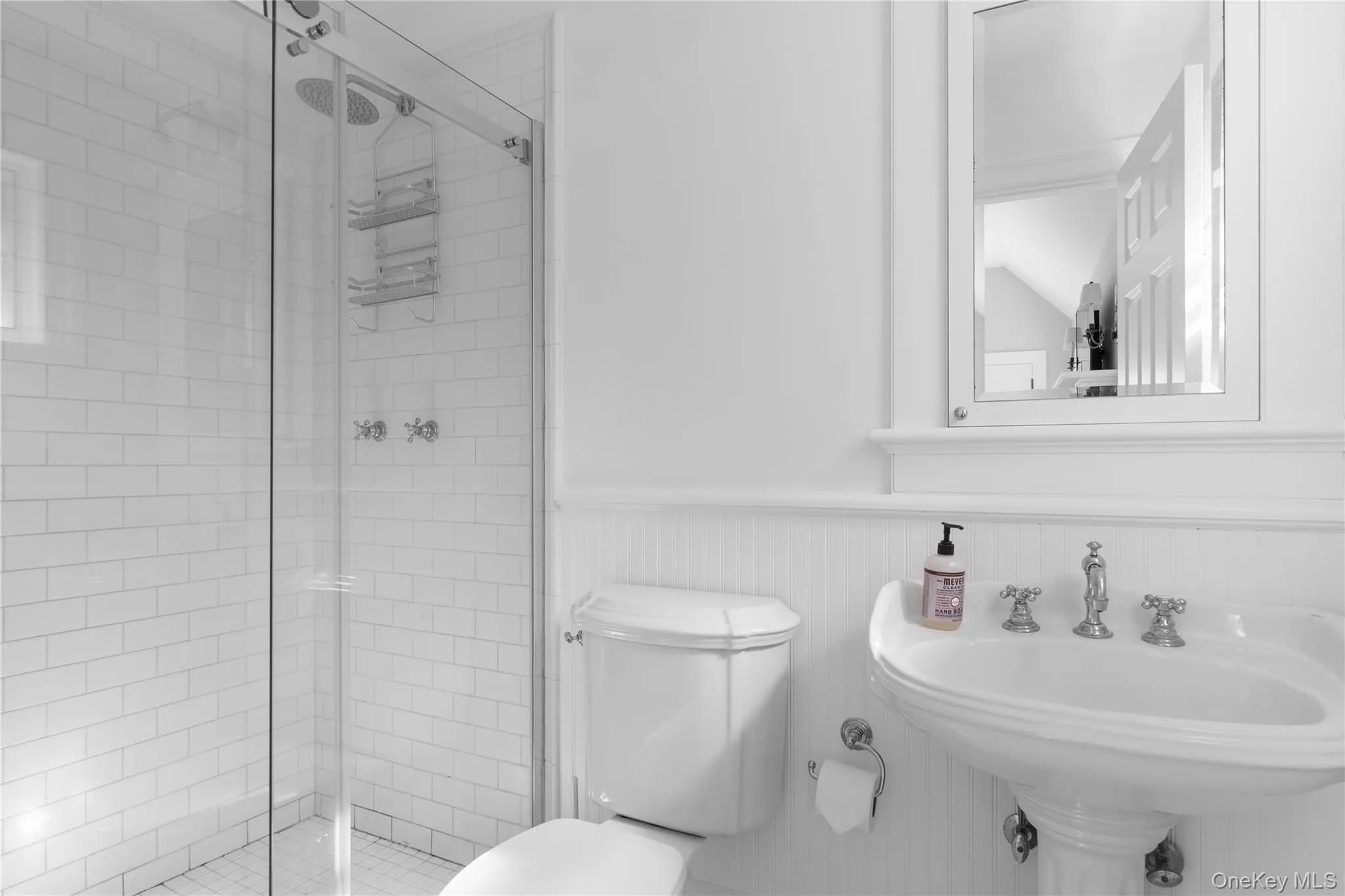 Bathroom with a shower stall, a wainscoted wall, a sink, and toilet Bathroom with a shower stall, a wainscoted wall, a sink, and toilet