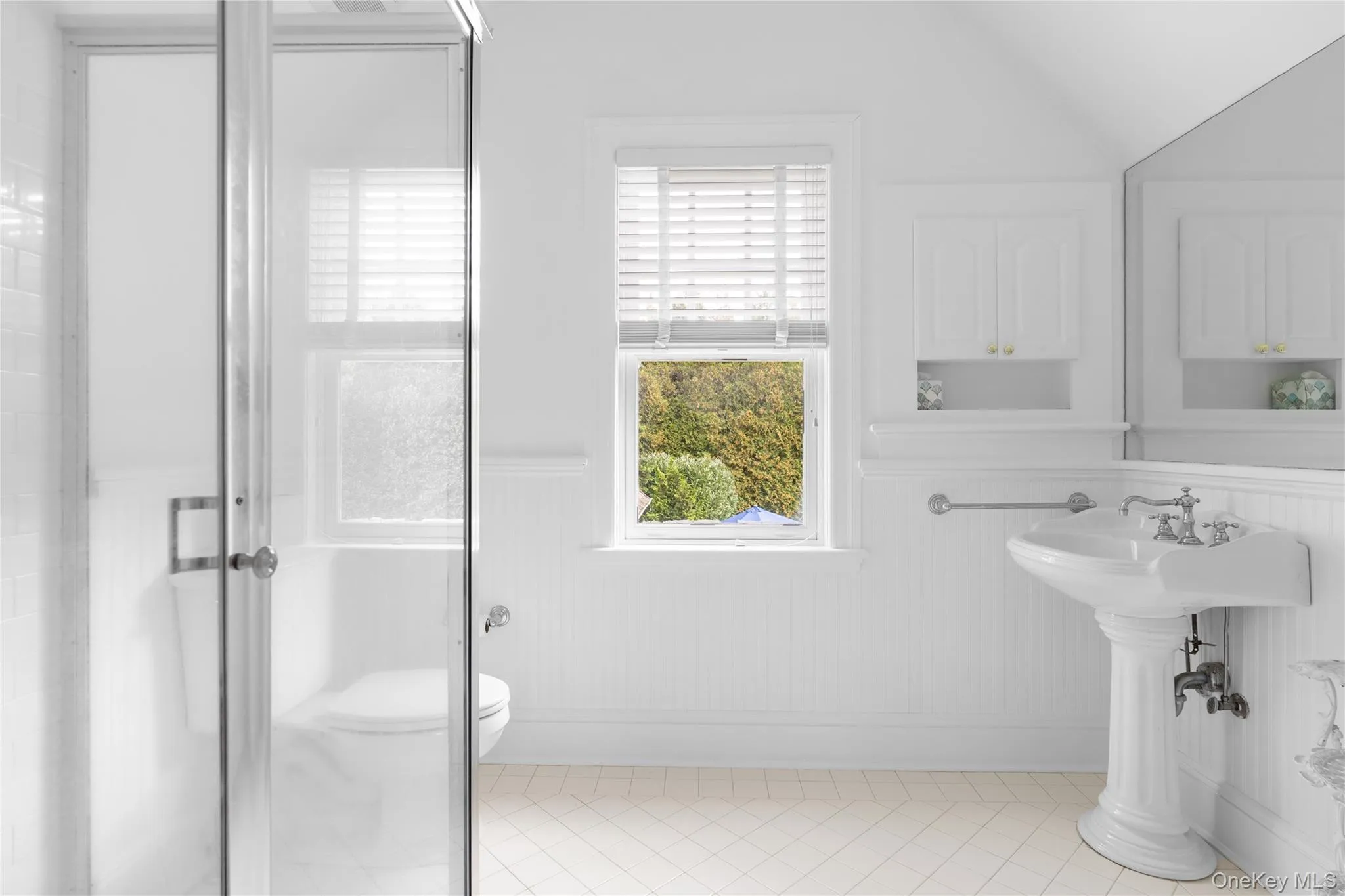 Bathroom featuring wainscoting, toilet, a healthy amount of sunlight, and tile patterned floors Bathroom featuring wainscoting, toilet, a healthy amount of sunlight, and tile patterned floors