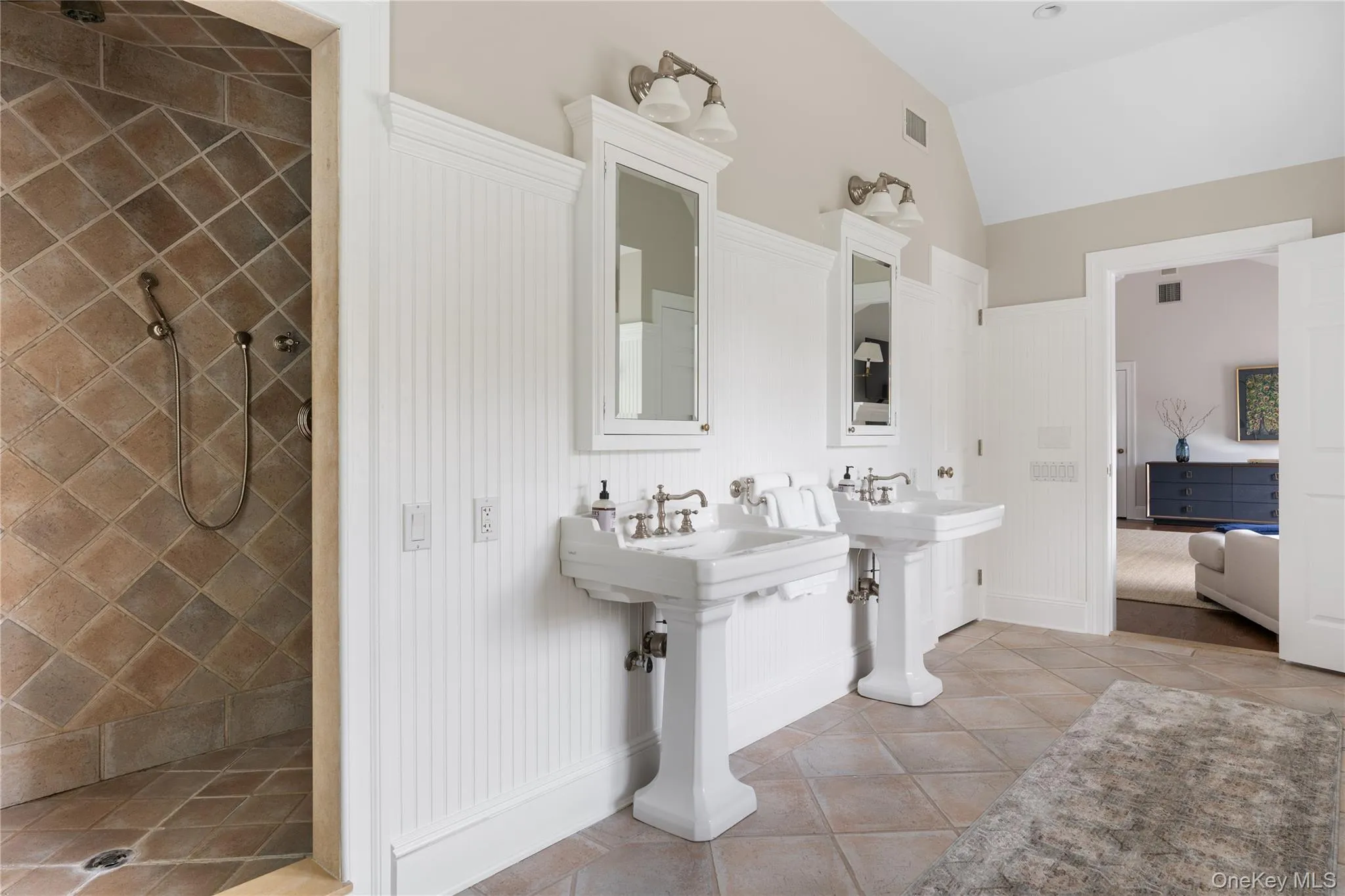 Full bath featuring a tile shower, lofted ceiling, tile patterned flooring, visible vents, and a decorative wall Full bath featuring a tile shower, lofted ceiling, tile patterned flooring, visible vents, and a decorative wall