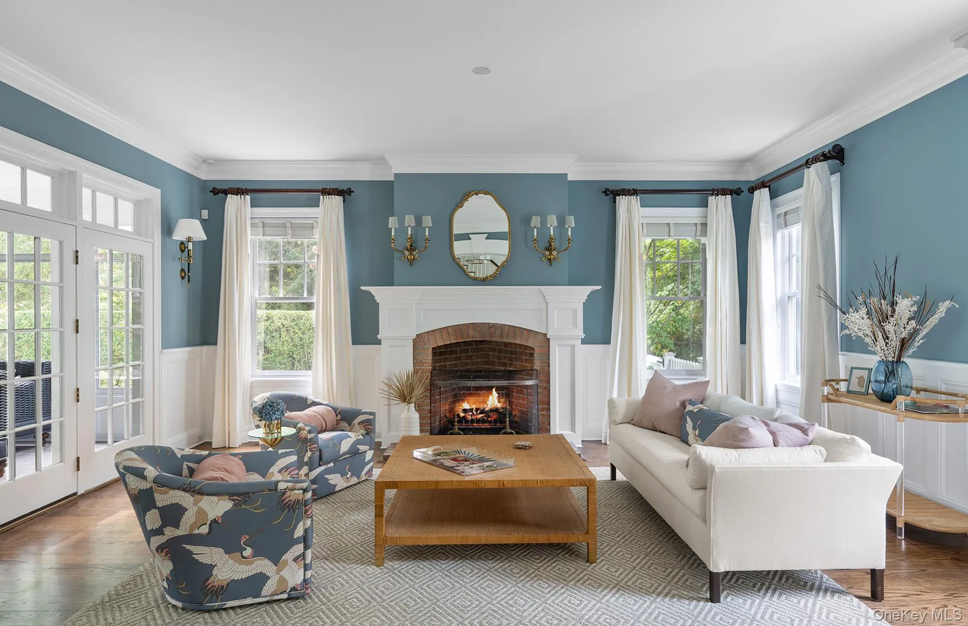 Living area featuring a healthy amount of sunlight, a wainscoted wall, wood finished floors, and a fireplace Living area featuring a healthy amount of sunlight, a wainscoted wall, wood finished floors, and a fireplace