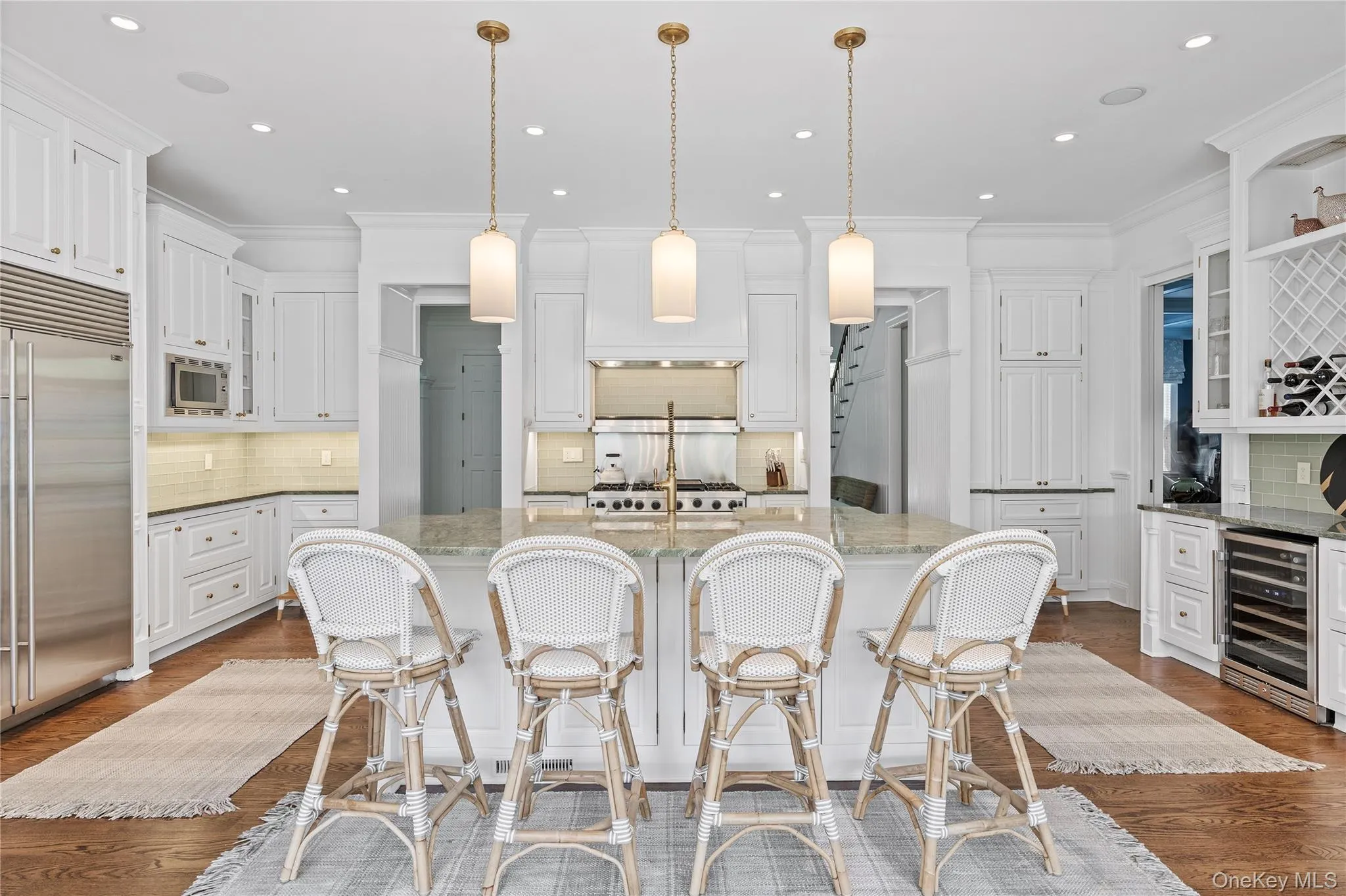 Kitchen featuring decorative backsplash, beverage cooler, glass insert cabinets, built in appliances, and a center island with sink Kitchen featuring decorative backsplash, beverage cooler, glass insert cabinets, built in appliances, and a center island with sink