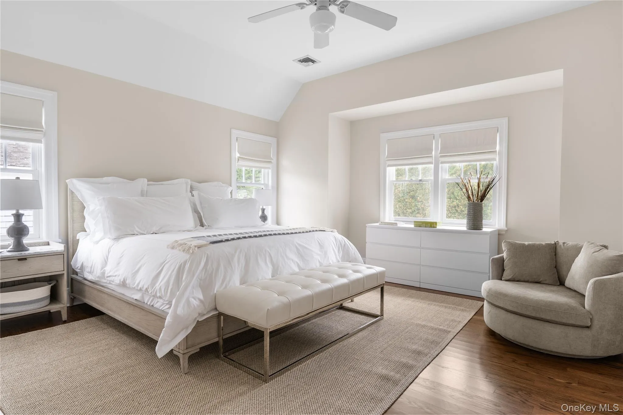 Bedroom with vaulted ceiling, wood finished floors, visible vents, and multiple windows Bedroom with vaulted ceiling, wood finished floors, visible vents, and multiple windows