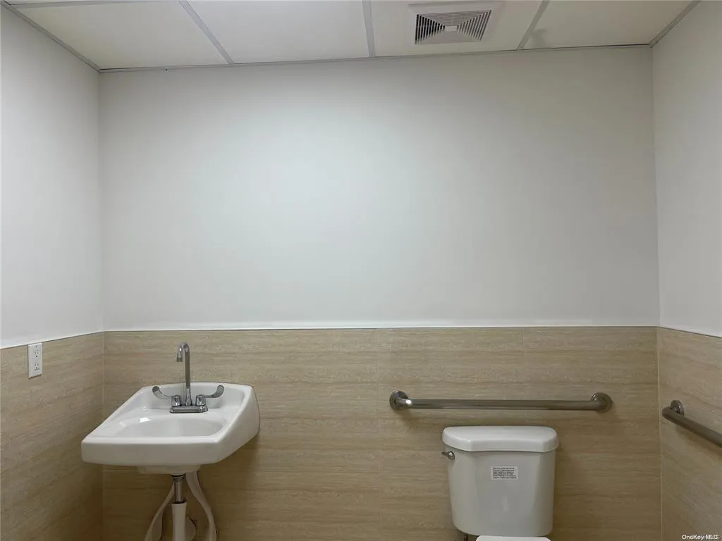 Bathroom with visible vents, a wainscoted wall, a sink, and toilet Bathroom with visible vents, a wainscoted wall, a sink, and toilet