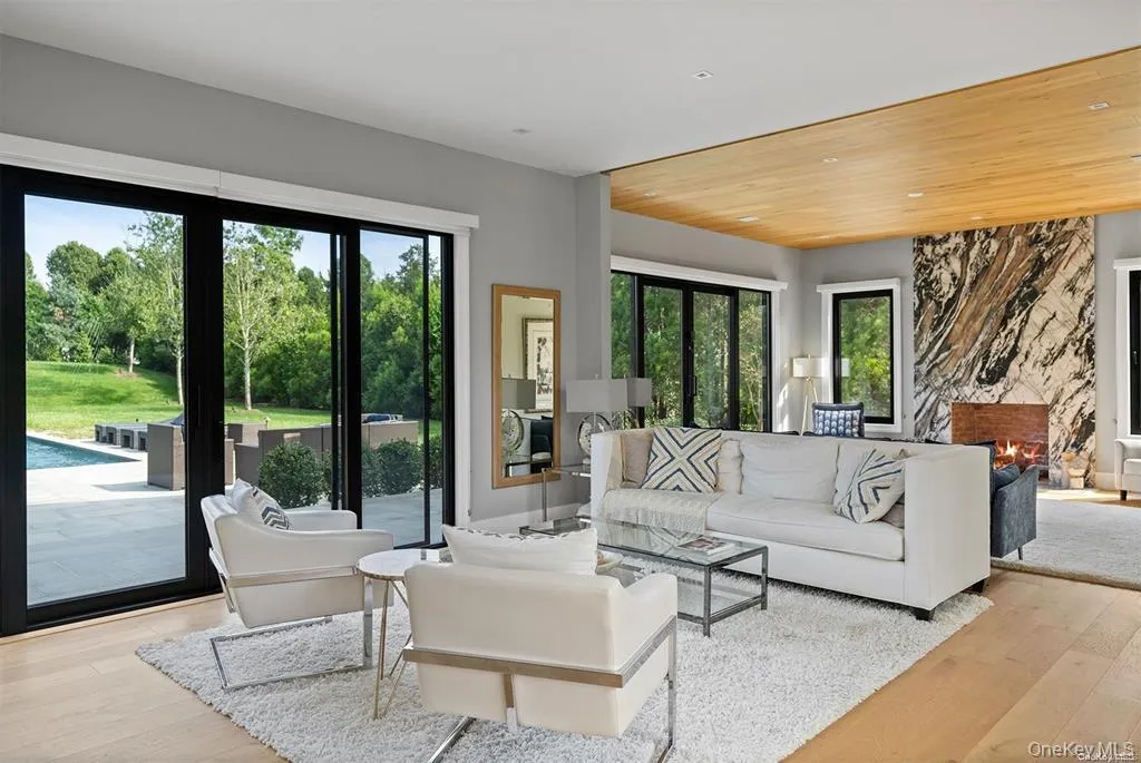 Living area featuring wood finished floors, a stone fireplace, wooden ceiling, and plenty of natural light Living area featuring wood finished floors, a stone fireplace, wooden ceiling, and plenty of natural light