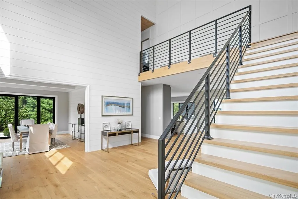 Staircase featuring wooden walls, wood finished floors, a high ceiling, and baseboards Staircase featuring wooden walls, wood finished floors, a high ceiling, and baseboards