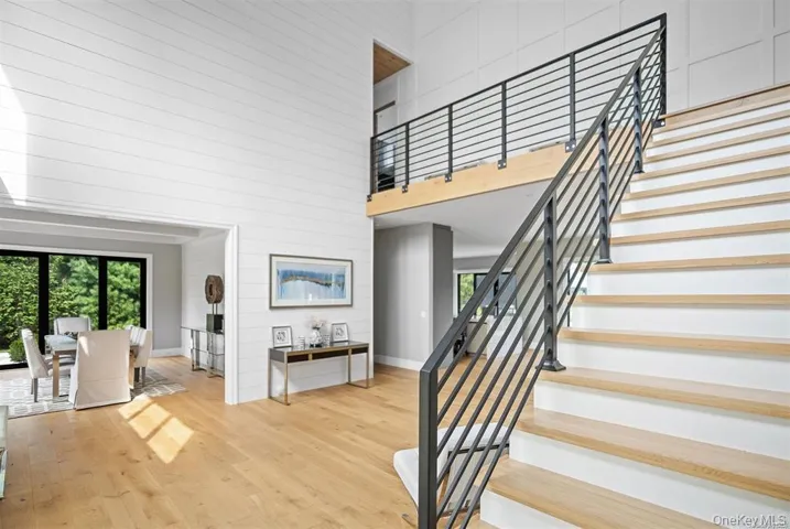 Staircase featuring wooden walls, wood finished floors, a high ceiling, and baseboards