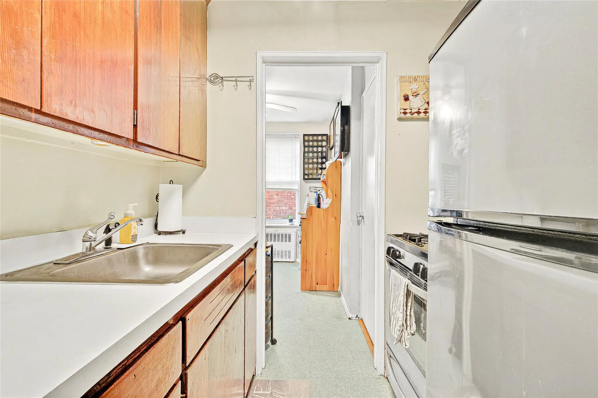 Kitchen featuring freestanding refrigerator, a sink, stainless steel gas range, light countertops, and light floors Kitchen featuring freestanding refrigerator, a sink, stainless steel gas range, light countertops, and light floors