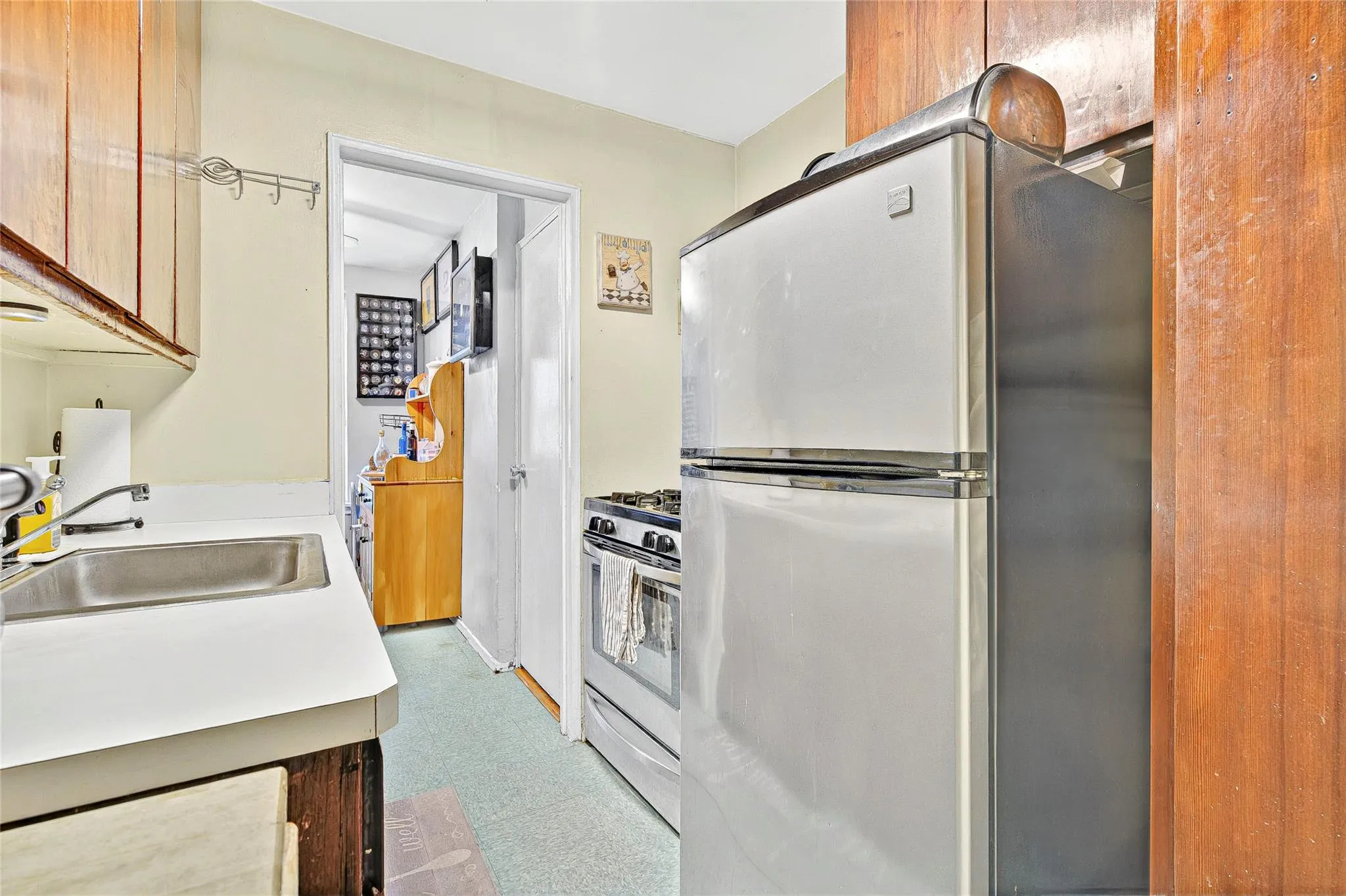 Kitchen with appliances with stainless steel finishes, a sink, tile patterned floors, and light countertops Kitchen with appliances with stainless steel finishes, a sink, tile patterned floors, and light countertops