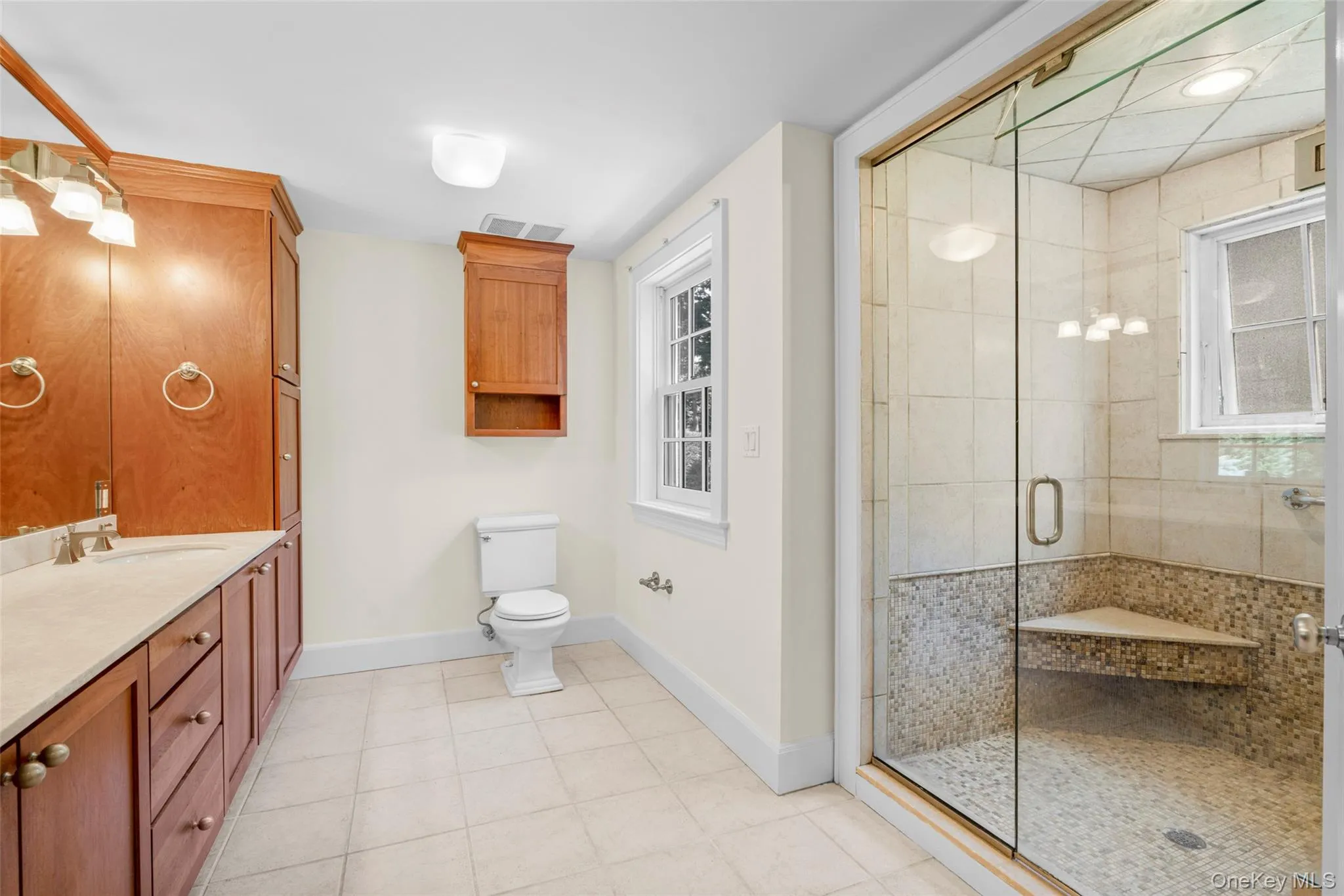 Primary bath with double sink vanity and walk in shower with bench. Primary bath with double sink vanity and walk in shower with bench.