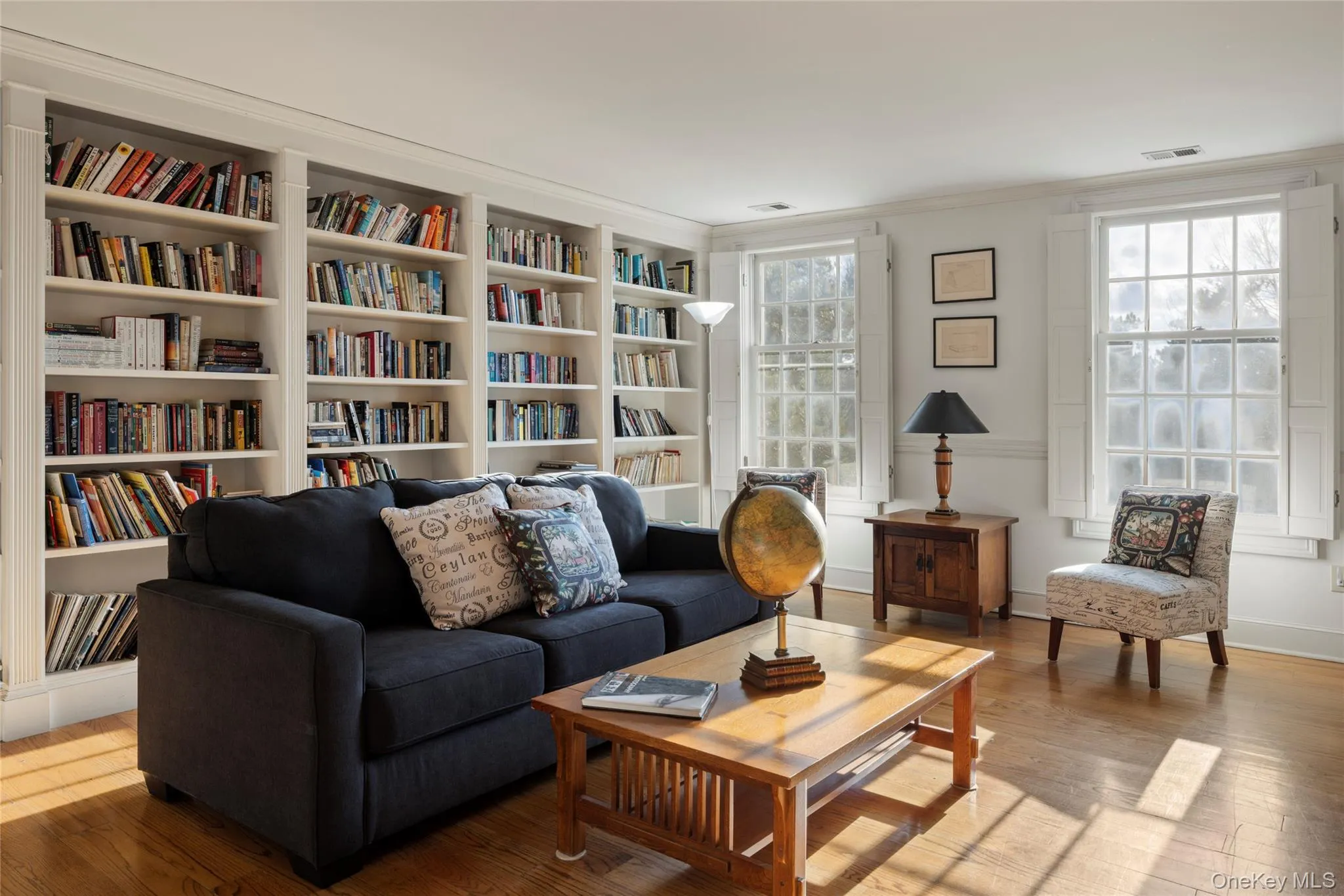 Sitting room with wood finished floors, visible vents, and crown molding Sitting room with wood finished floors, visible vents, and crown molding