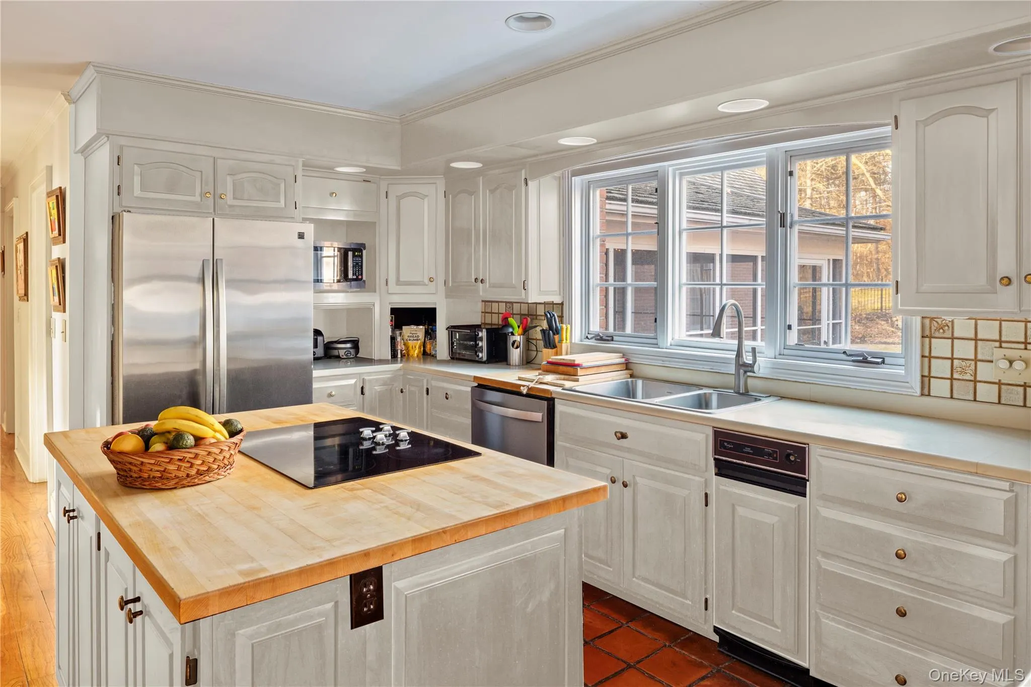 Kitchen featuring a sink, white cabinetry, decorative backsplash, wood counters, and appliances with stainless steel finishes Kitchen featuring a sink, white cabinetry, decorative backsplash, wood counters, and appliances with stainless steel finishes