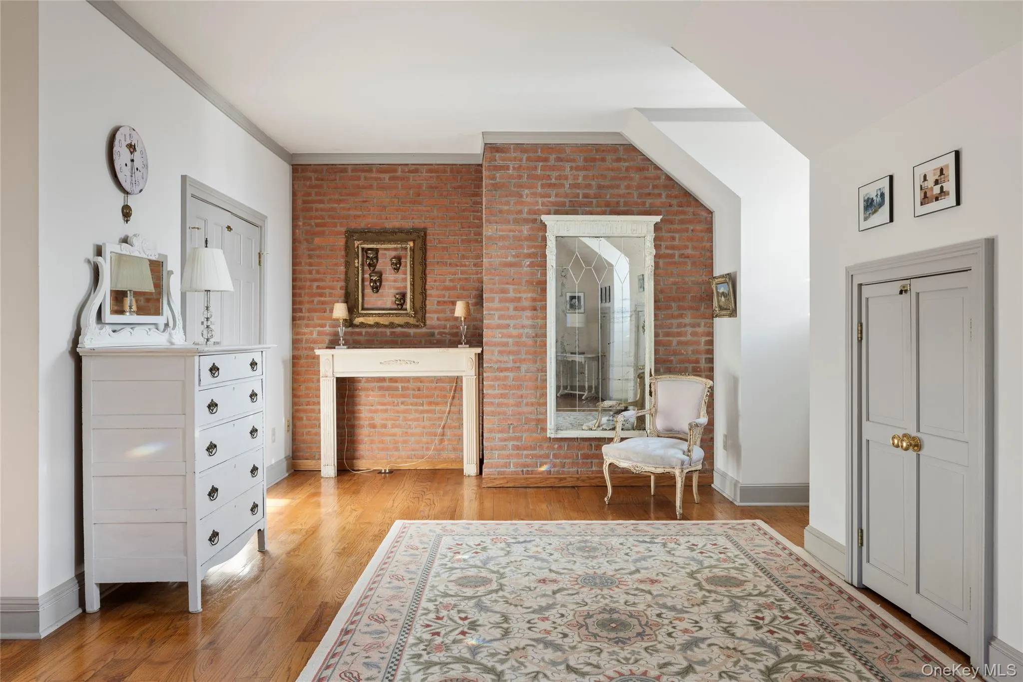 Sitting room with light wood-type flooring, baseboards, and brick wall Sitting room with light wood-type flooring, baseboards, and brick wall