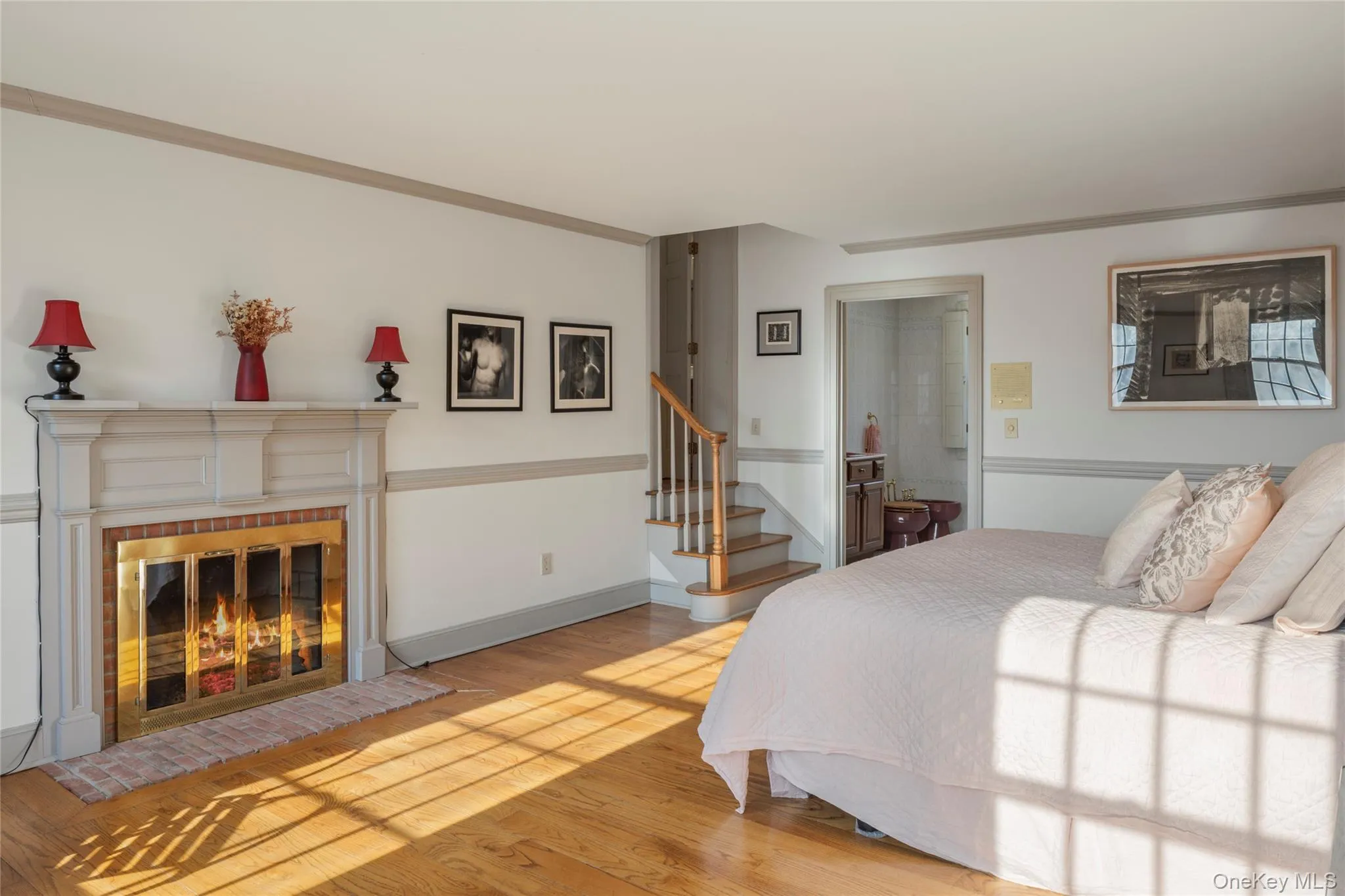 Bedroom with crown molding, wood finished floors, and a fireplace Bedroom with crown molding, wood finished floors, and a fireplace