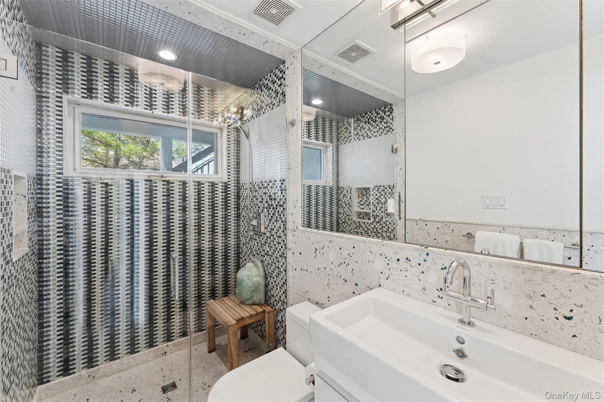 Bathroom featuring tile walls, visible vents, a shower stall, and toilet Bathroom featuring tile walls, visible vents, a shower stall, and toilet
