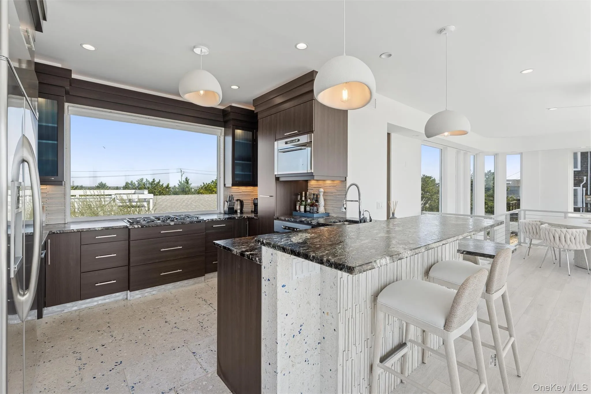 Kitchen with a breakfast bar area, modern cabinets, dark brown cabinetry, and a peninsula Kitchen with a breakfast bar area, modern cabinets, dark brown cabinetry, and a peninsula