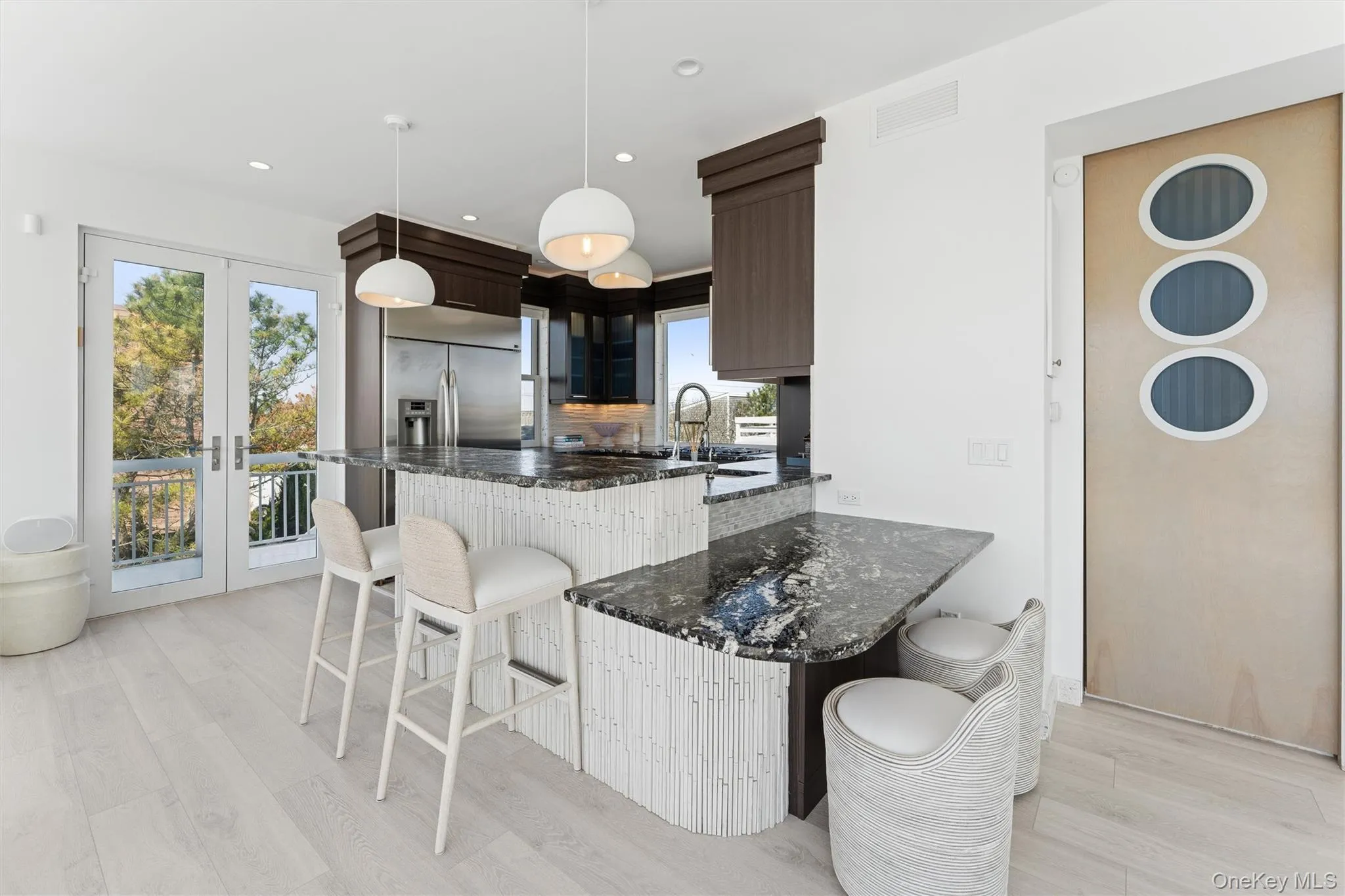 Kitchen with dark stone countertops, a kitchen bar, and light wood finished floors Kitchen with dark stone countertops, a kitchen bar, and light wood finished floors