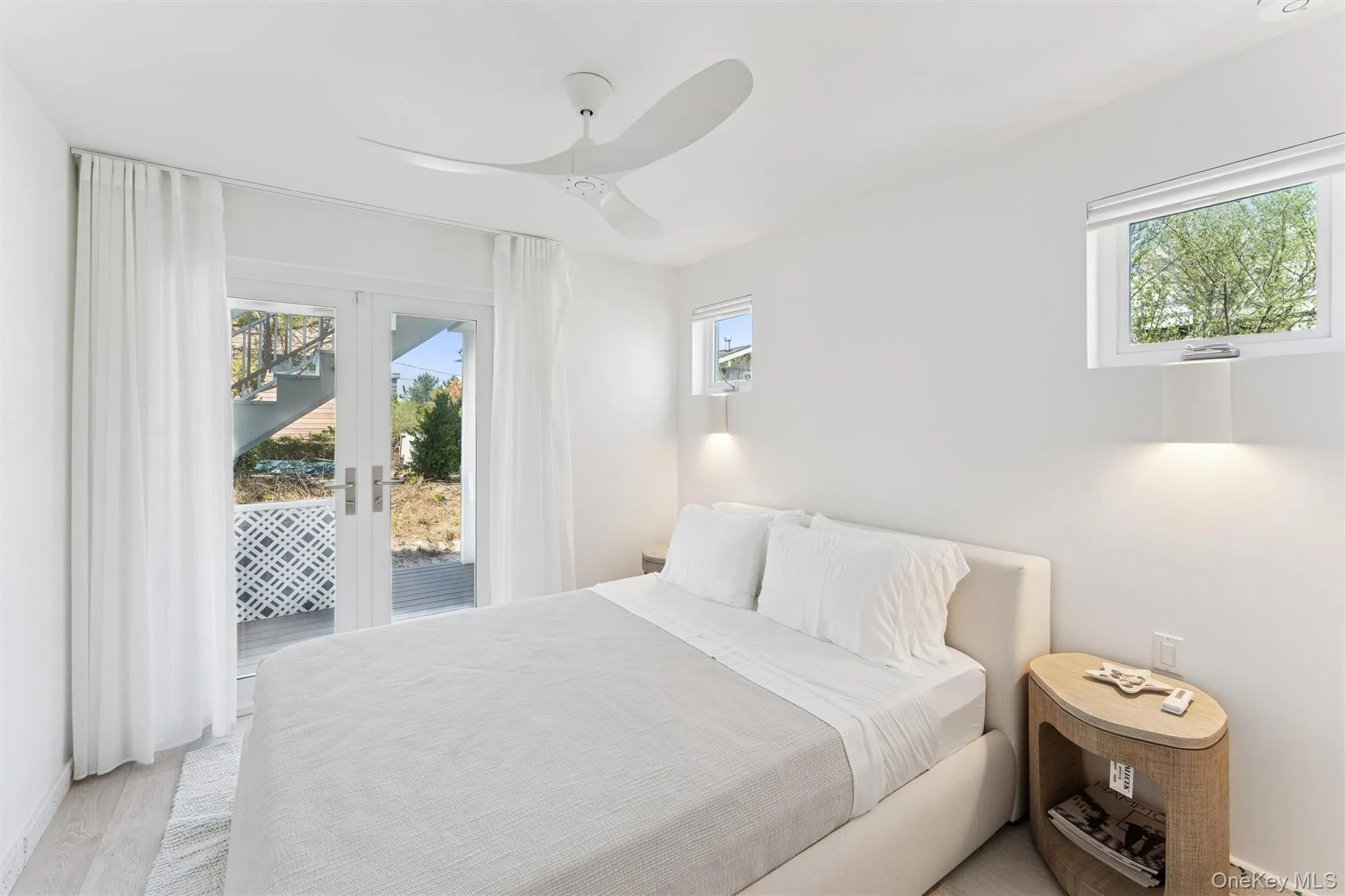 Bedroom featuring french doors, light wood-style floors, access to exterior, and multiple windows Bedroom featuring french doors, light wood-style floors, access to exterior, and multiple windows