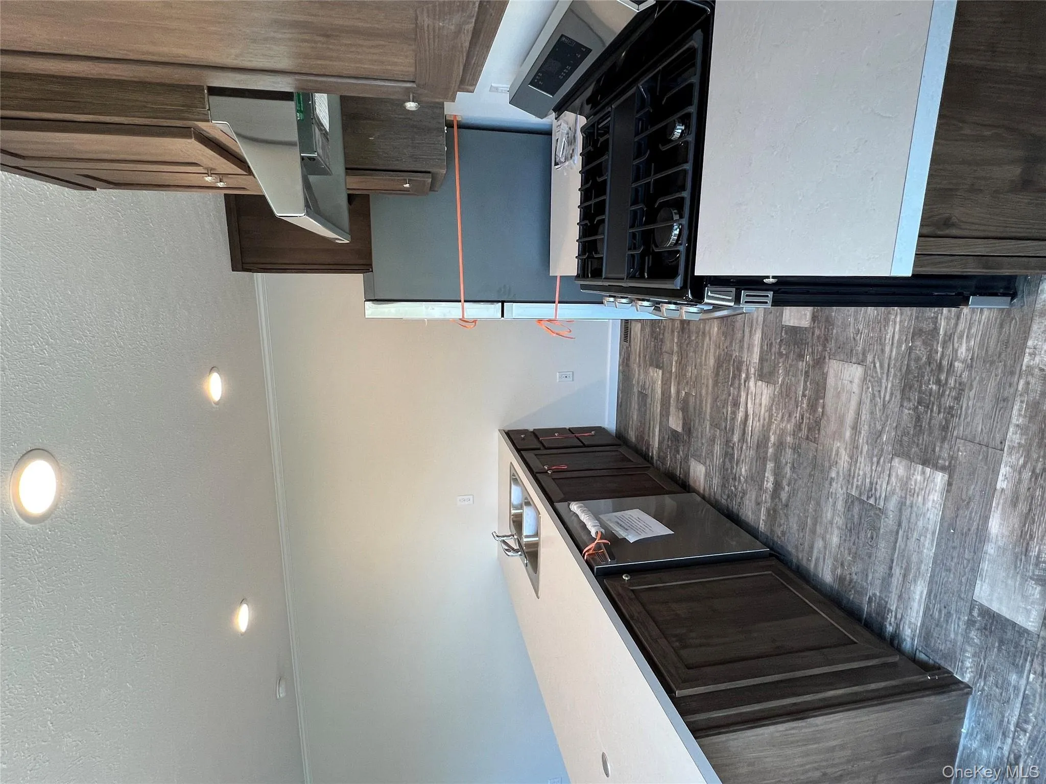 Kitchen featuring range hood, a sink, stove, dark brown cabinetry, and dishwasher Kitchen featuring range hood, a sink, stove, dark brown cabinetry, and dishwasher