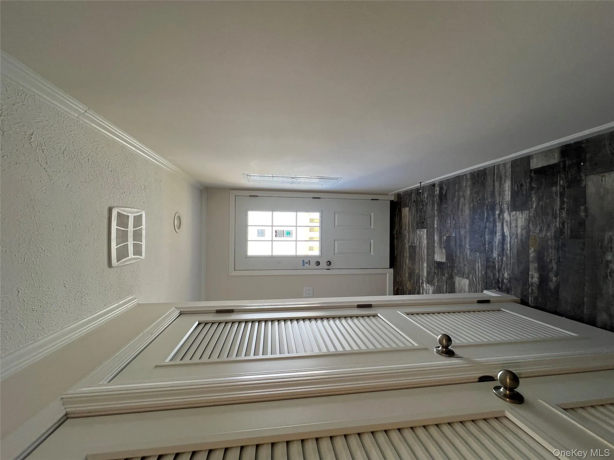 Doorway to outside with dark wood-type flooring, crown molding, visible vents, baseboards, and a textured ceiling Doorway to outside with dark wood-type flooring, crown molding, visible vents, baseboards, and a textured ceiling