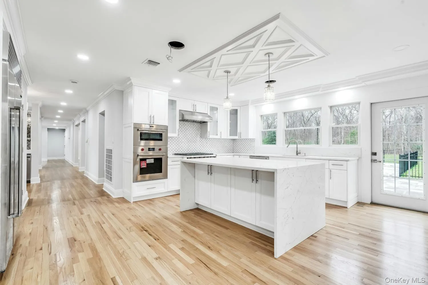 Kitchen featuring visible vents, crown molding, light countertops, white cabinets, and under cabinet range hood Kitchen featuring visible vents, crown molding, light countertops, white cabinets, and under cabinet range hood