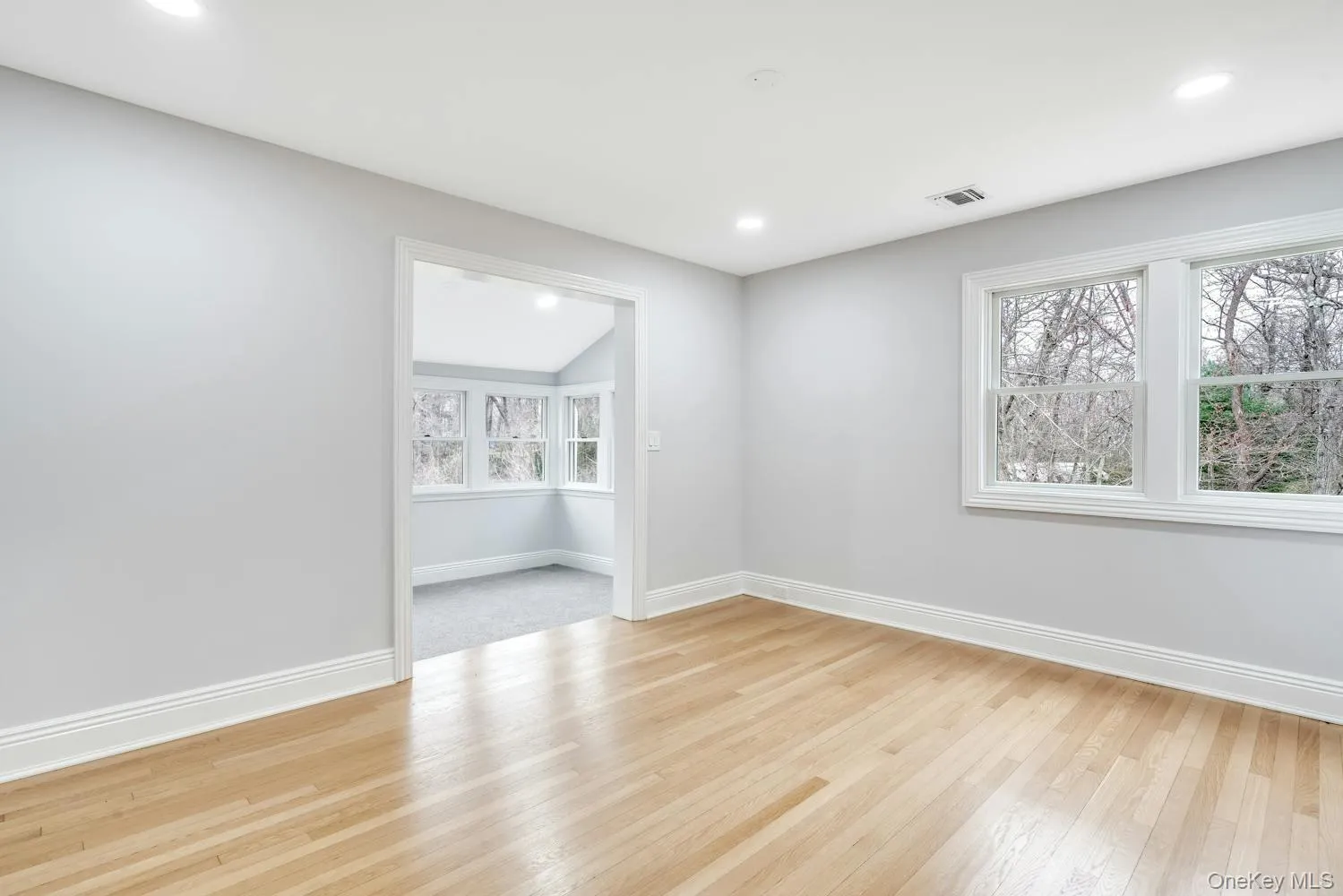 Empty room featuring light wood-style floors, baseboards, a wealth of natural light, and visible vents Empty room featuring light wood-style floors, baseboards, a wealth of natural light, and visible vents