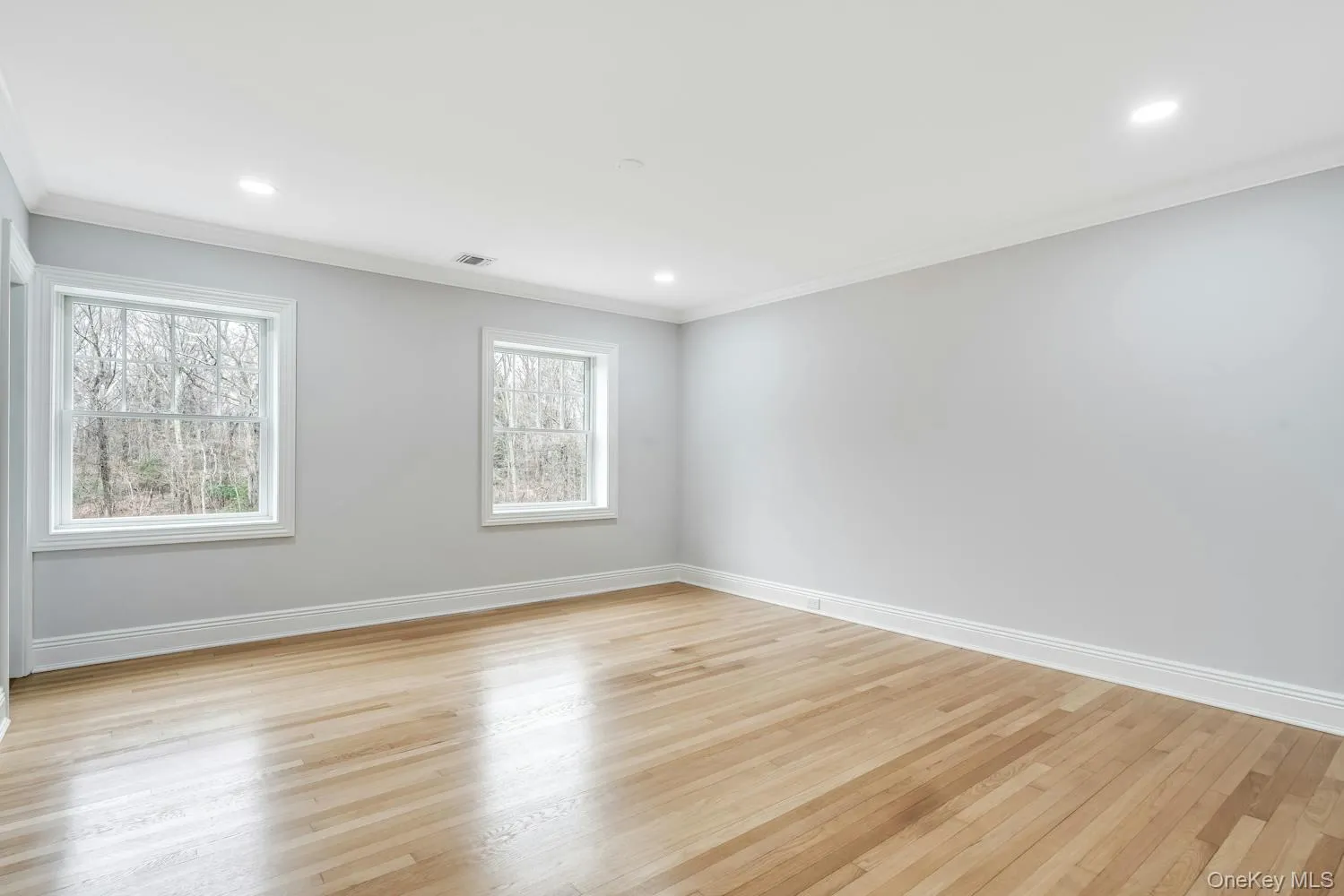 Empty room with baseboards, ornamental molding, and plenty of natural light Empty room with baseboards, ornamental molding, and plenty of natural light