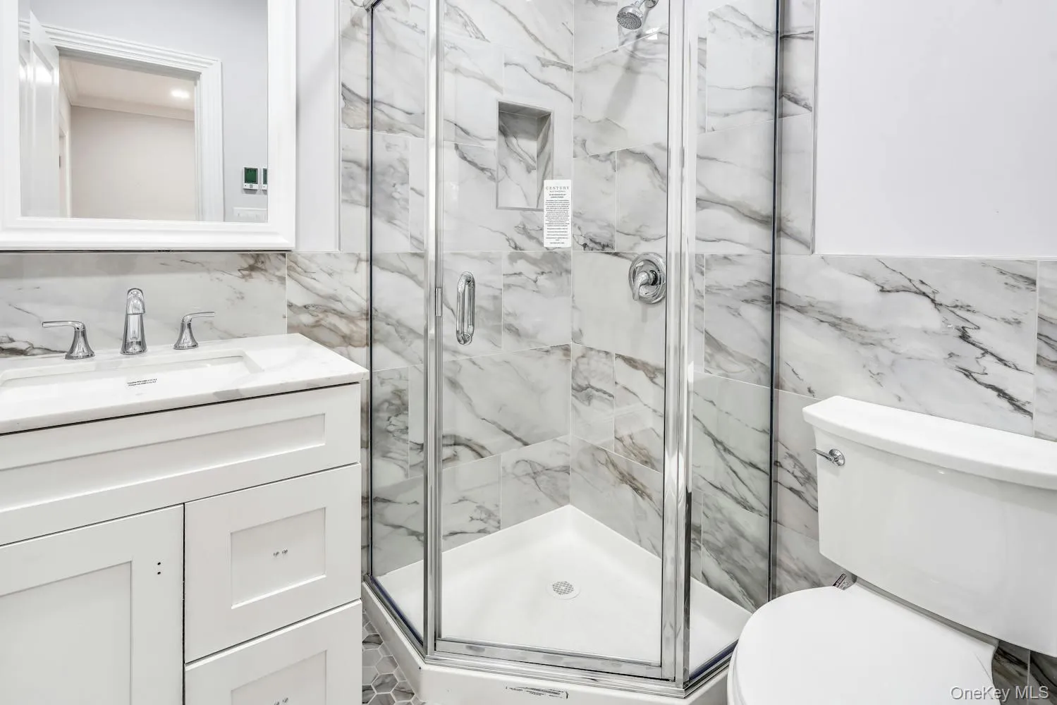 Full bathroom featuring tile walls, vanity, toilet, and a marble finish shower Full bathroom featuring tile walls, vanity, toilet, and a marble finish shower