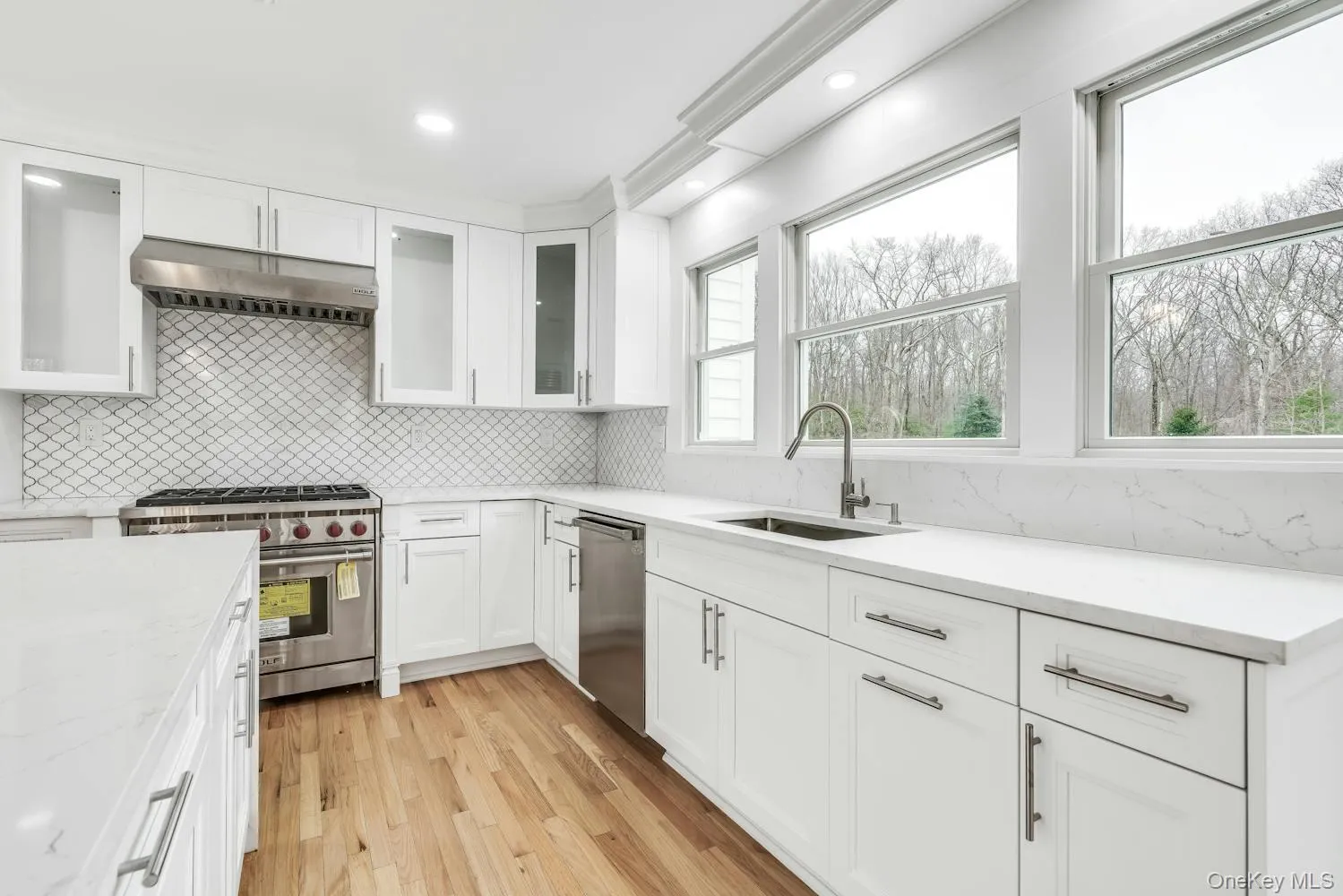 Kitchen featuring a sink, backsplash, under cabinet range hood, and stainless steel appliances Kitchen featuring a sink, backsplash, under cabinet range hood, and stainless steel appliances