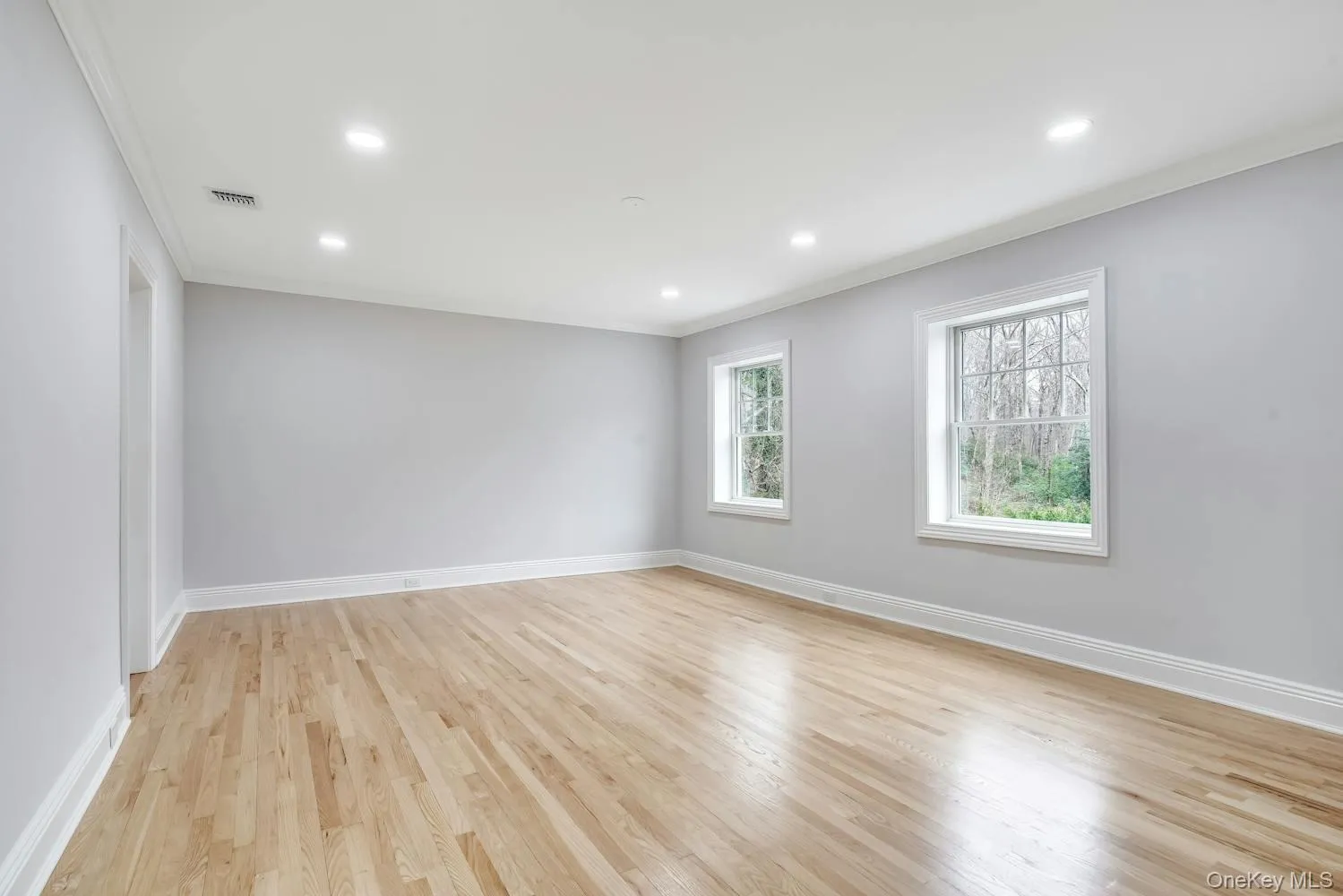 Empty room featuring baseboards, visible vents, ornamental molding, and light wood-type flooring Empty room featuring baseboards, visible vents, ornamental molding, and light wood-type flooring