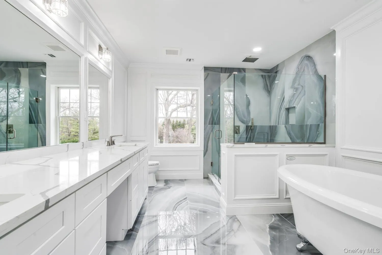 Bathroom with double vanity, a freestanding tub, a decorative wall, a sink, and a marble finish shower Bathroom with double vanity, a freestanding tub, a decorative wall, a sink, and a marble finish shower