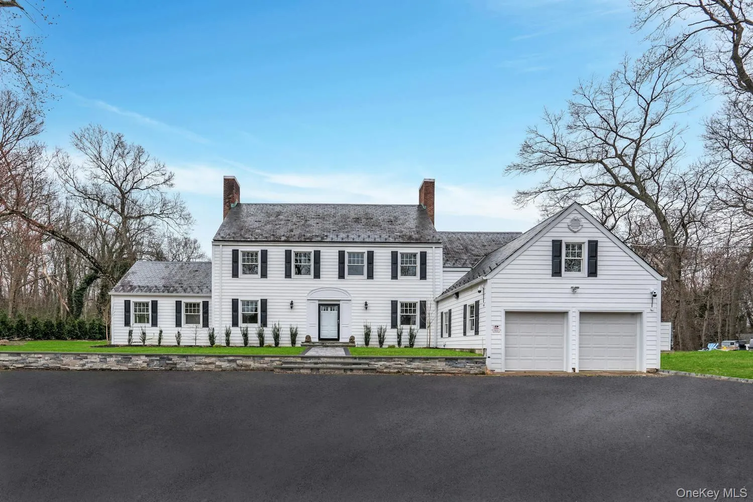 Colonial inspired home with a garage, driveway, and a chimney Colonial inspired home with a garage, driveway, and a chimney