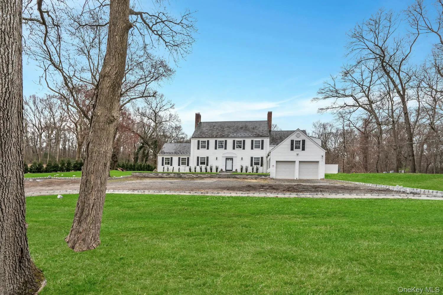 View of front facade featuring a chimney, a front yard, and a garage View of front facade featuring a chimney, a front yard, and a garage