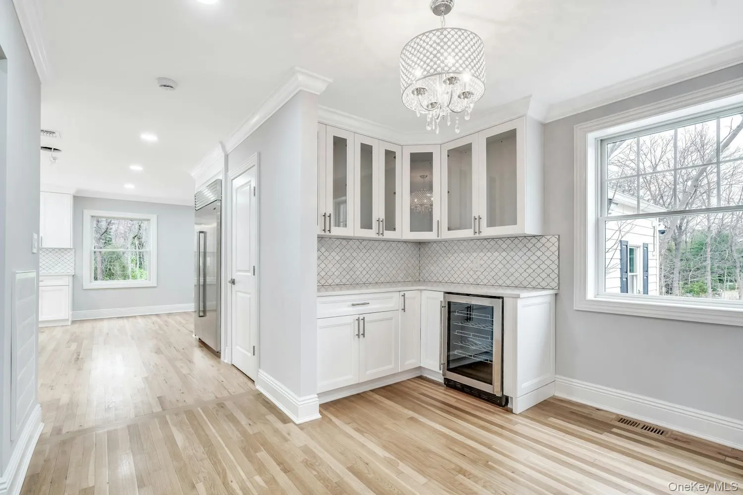 Bar featuring light wood finished floors, beverage cooler, stainless steel built in fridge, visible vents, and ornamental molding Bar featuring light wood finished floors, beverage cooler, stainless steel built in fridge, visible vents, and ornamental molding