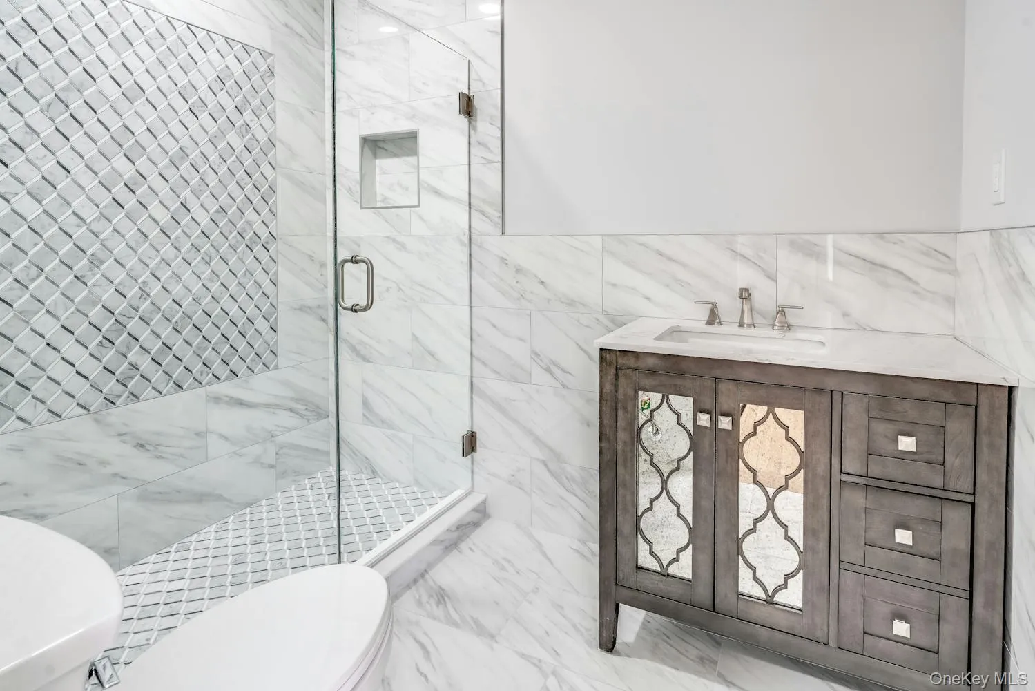 Full bath with wainscoting, a sink, toilet, tile walls, and a shower stall Full bath with wainscoting, a sink, toilet, tile walls, and a shower stall