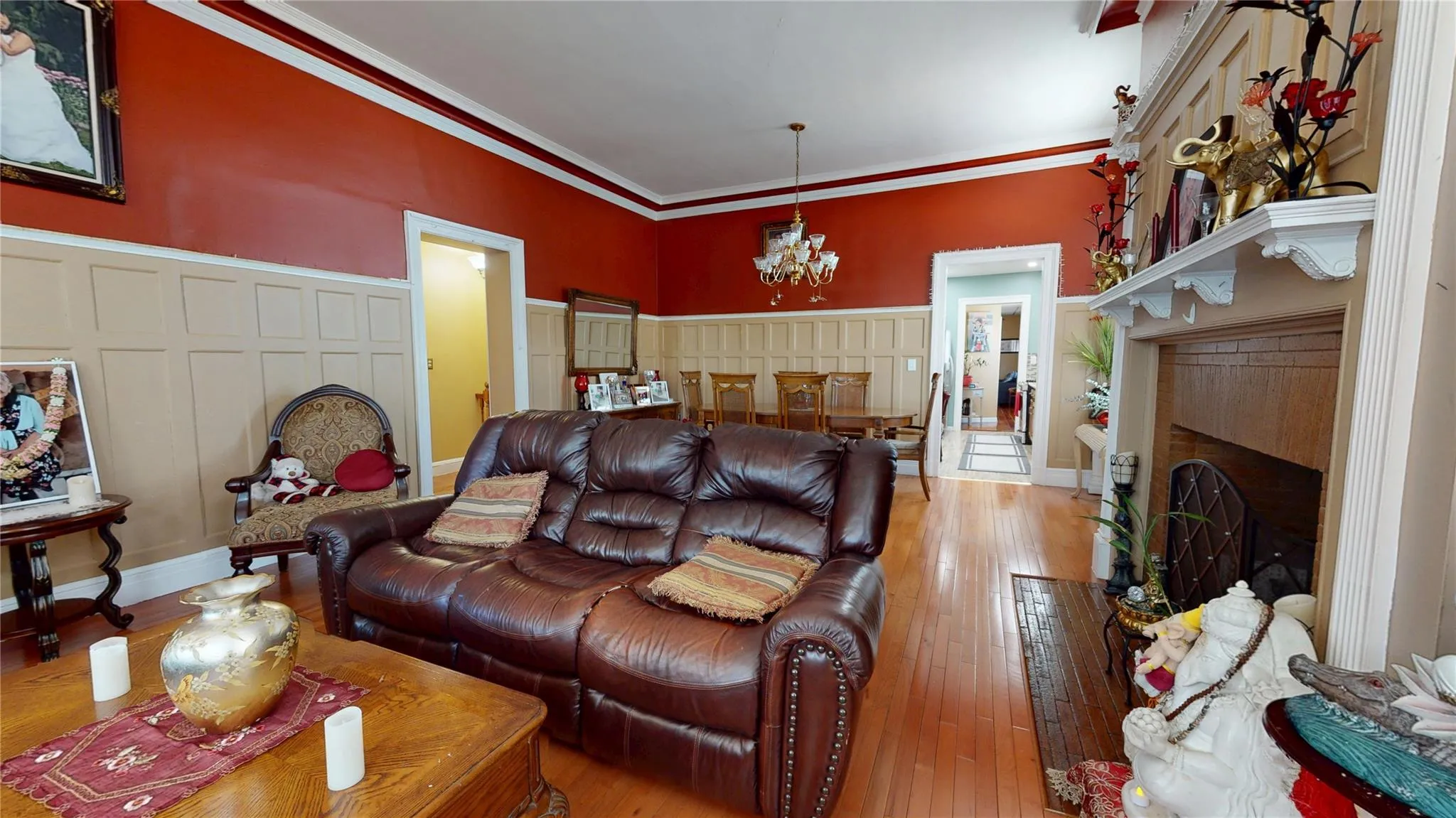 Living area with a chandelier, a fireplace, a decorative wall, ornamental molding, and hardwood / wood-style floors Living area with a chandelier, a fireplace, a decorative wall, ornamental molding, and hardwood / wood-style floors