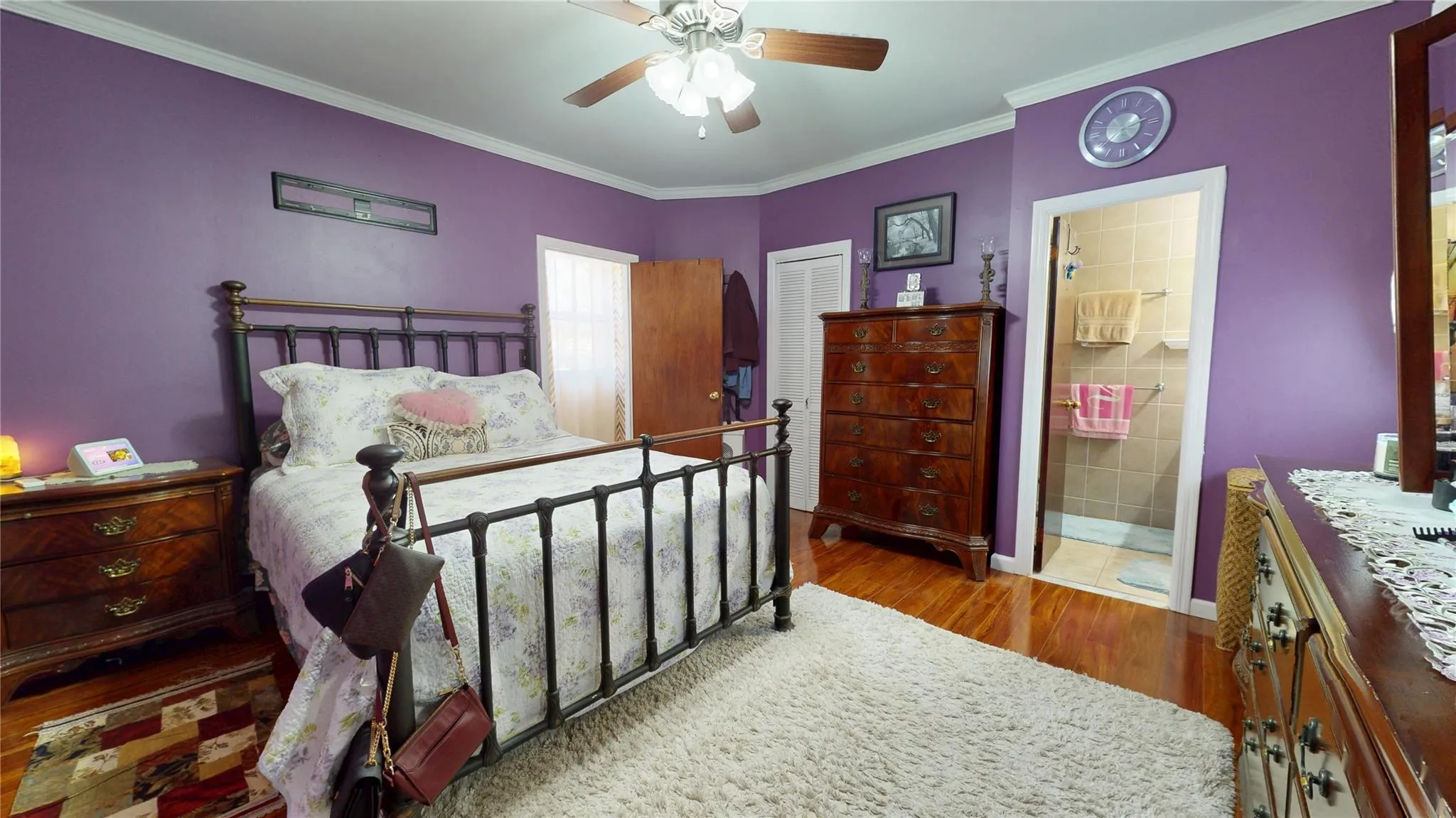 Bedroom featuring a closet, a ceiling fan, ornamental molding, wood finished floors, and ensuite bathroom Bedroom featuring a closet, a ceiling fan, ornamental molding, wood finished floors, and ensuite bathroom