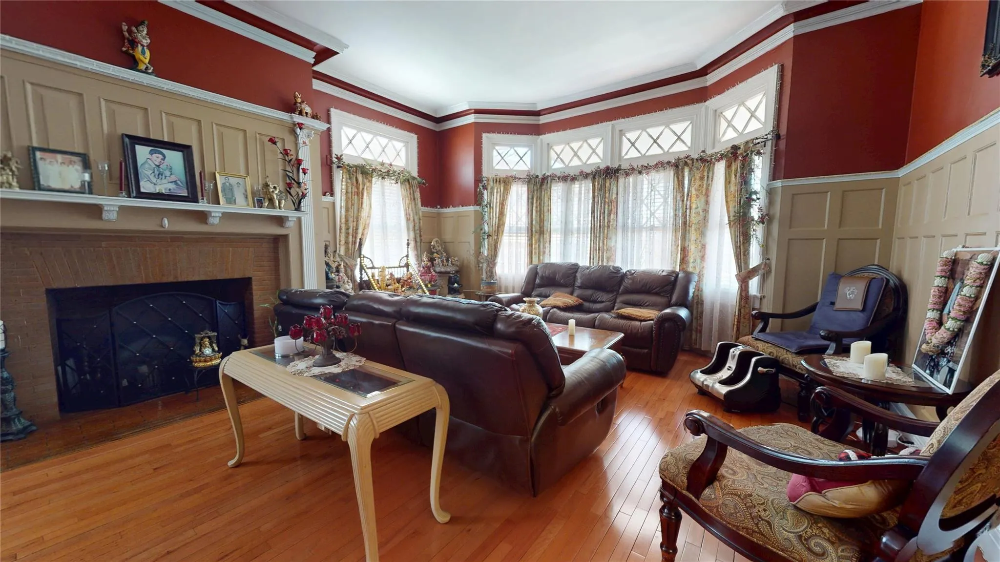 Living area with a fireplace, crown molding, a decorative wall, hardwood / wood-style floors, and wainscoting Living area with a fireplace, crown molding, a decorative wall, hardwood / wood-style floors, and wainscoting
