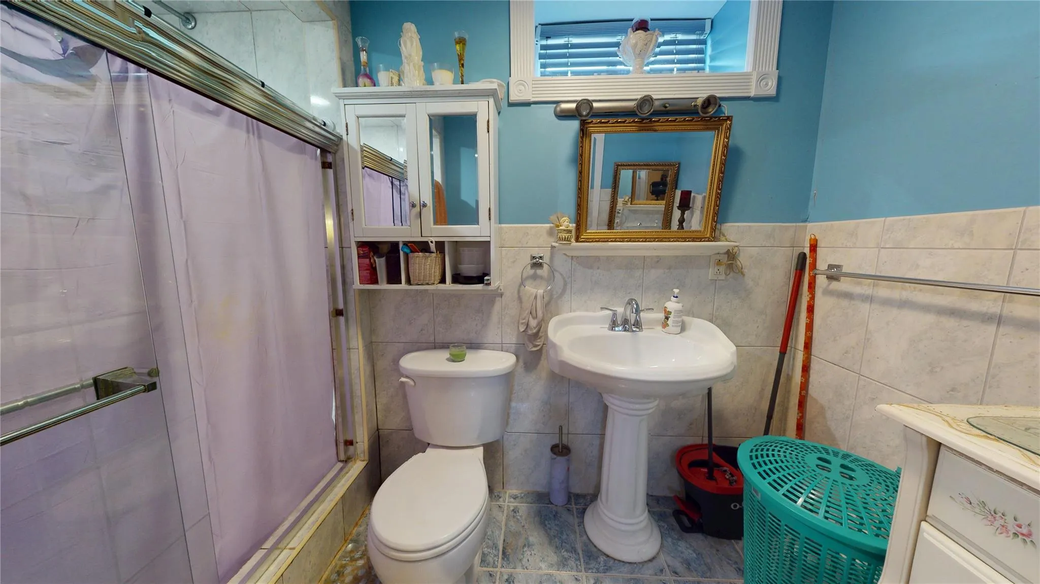 Full bath with tile walls, a shower with shower curtain, toilet, and a sink Full bath with tile walls, a shower with shower curtain, toilet, and a sink