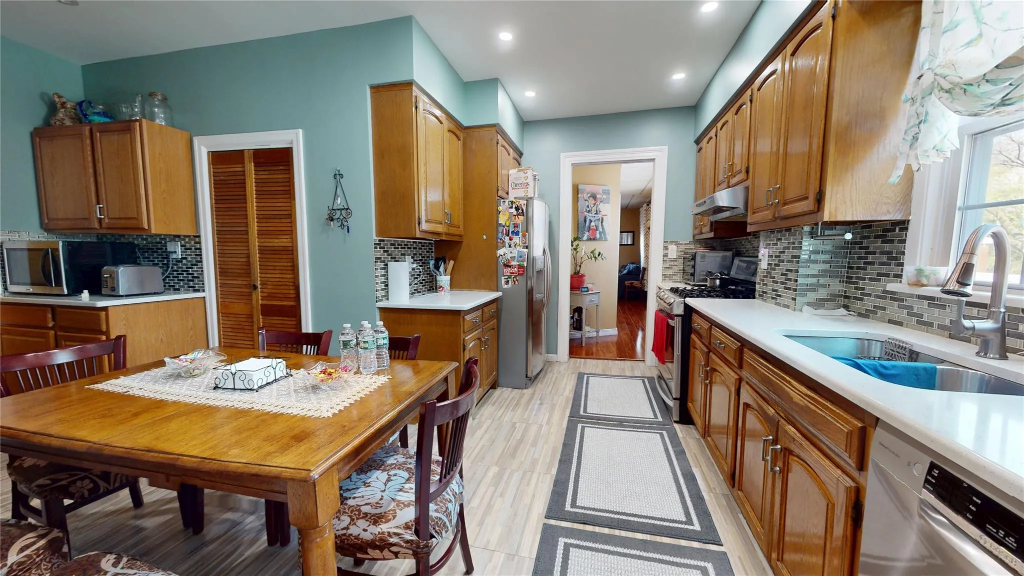 Kitchen with stainless steel appliances, under cabinet range hood, light countertops, backsplash, and a sink Kitchen with stainless steel appliances, under cabinet range hood, light countertops, backsplash, and a sink