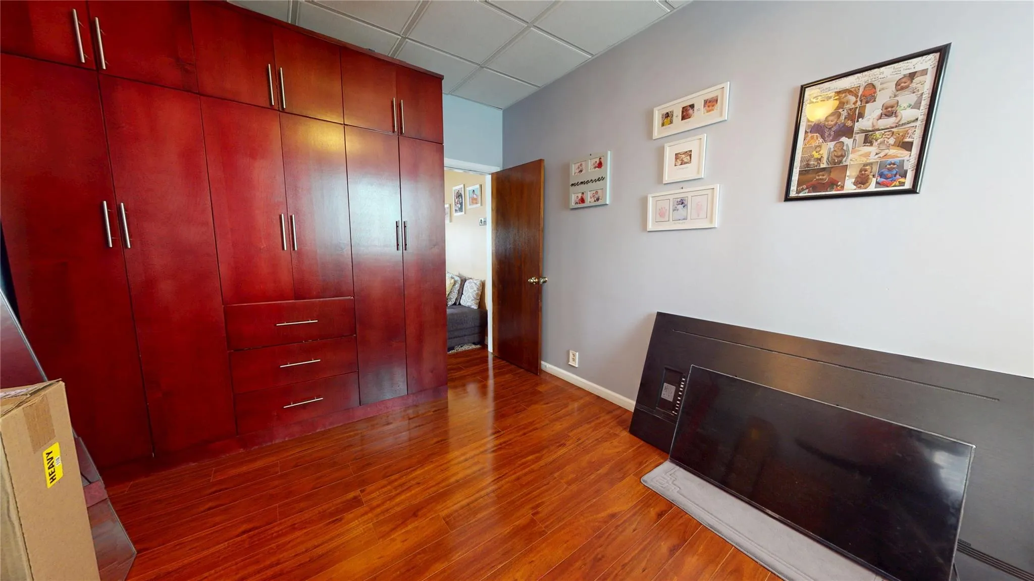 Bedroom featuring wood finished floors, a paneled ceiling, and baseboards Bedroom featuring wood finished floors, a paneled ceiling, and baseboards